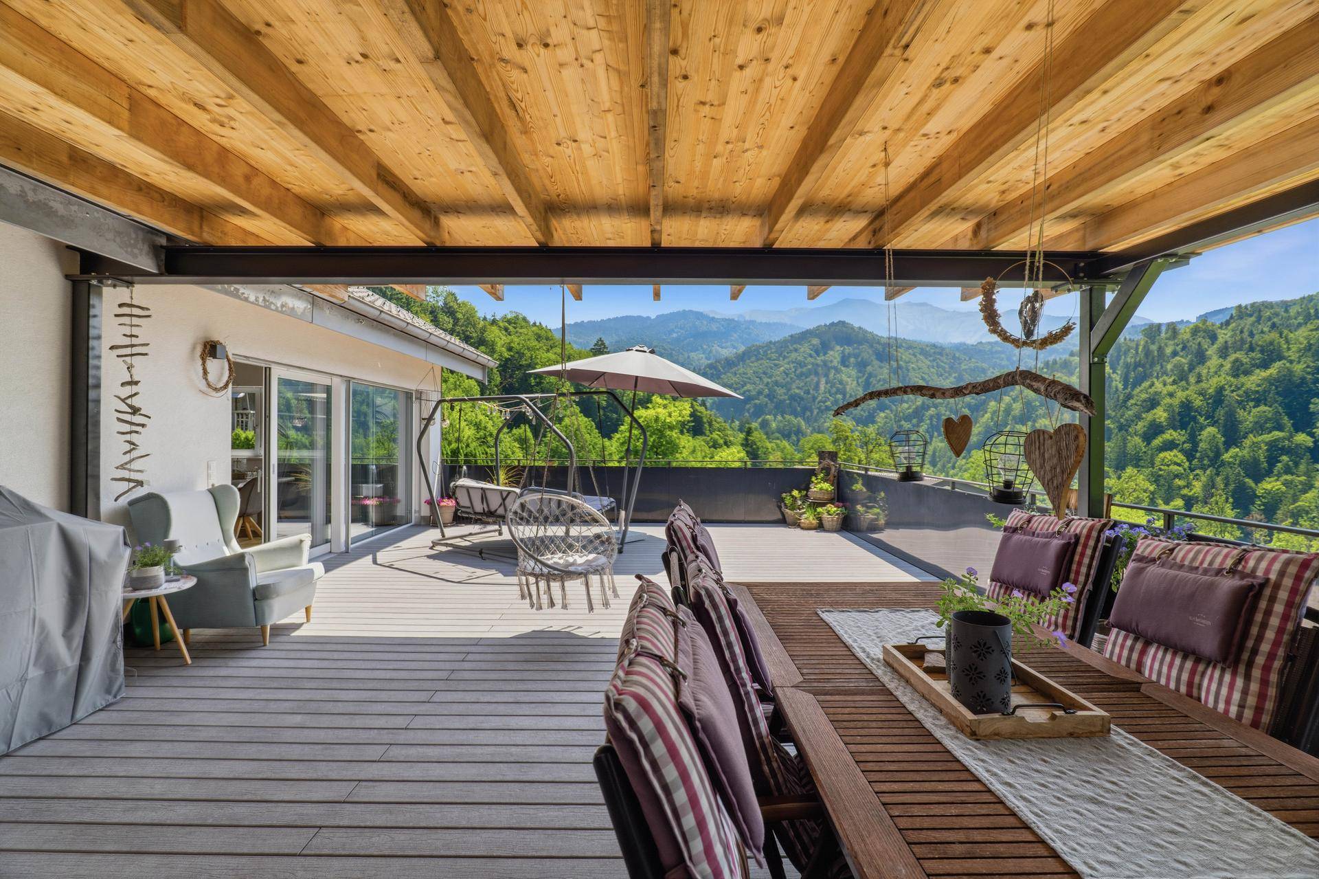 Große überdachte Terrasse mit Essbereich, Lounge-Möbeln und Bergblick.