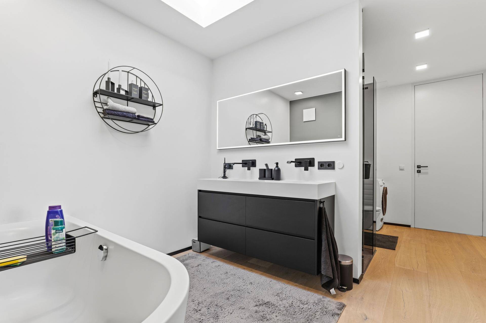 Helles Badezimmer mit modernem Doppelwaschtisch, beleuchtetem Spiegel und Badewanne.