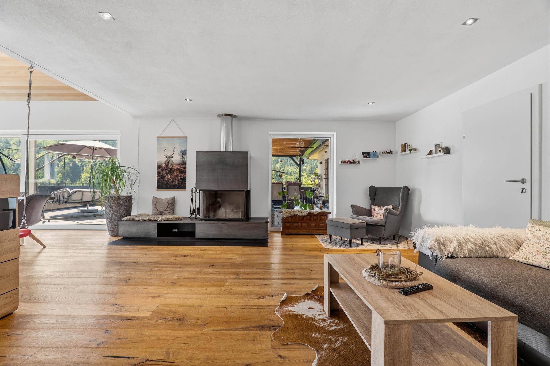 Geräumiges Wohnzimmer mit Holzboden, modernem Kamin und Terrassenzugang.
