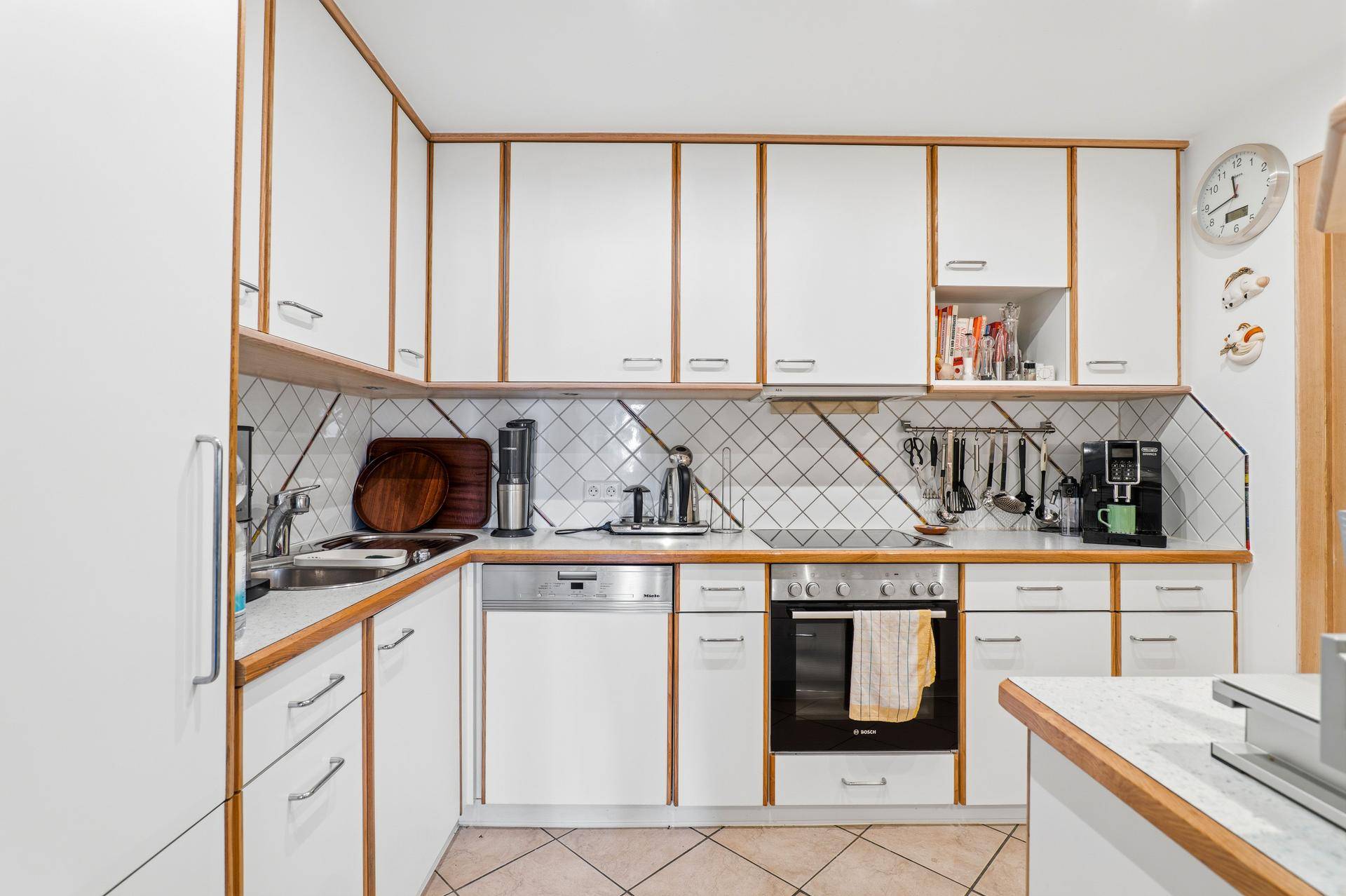 Funktionale Küche mit weißen Schränken, Holz-Arbeitsplatten und modernen Einbaugeräten.