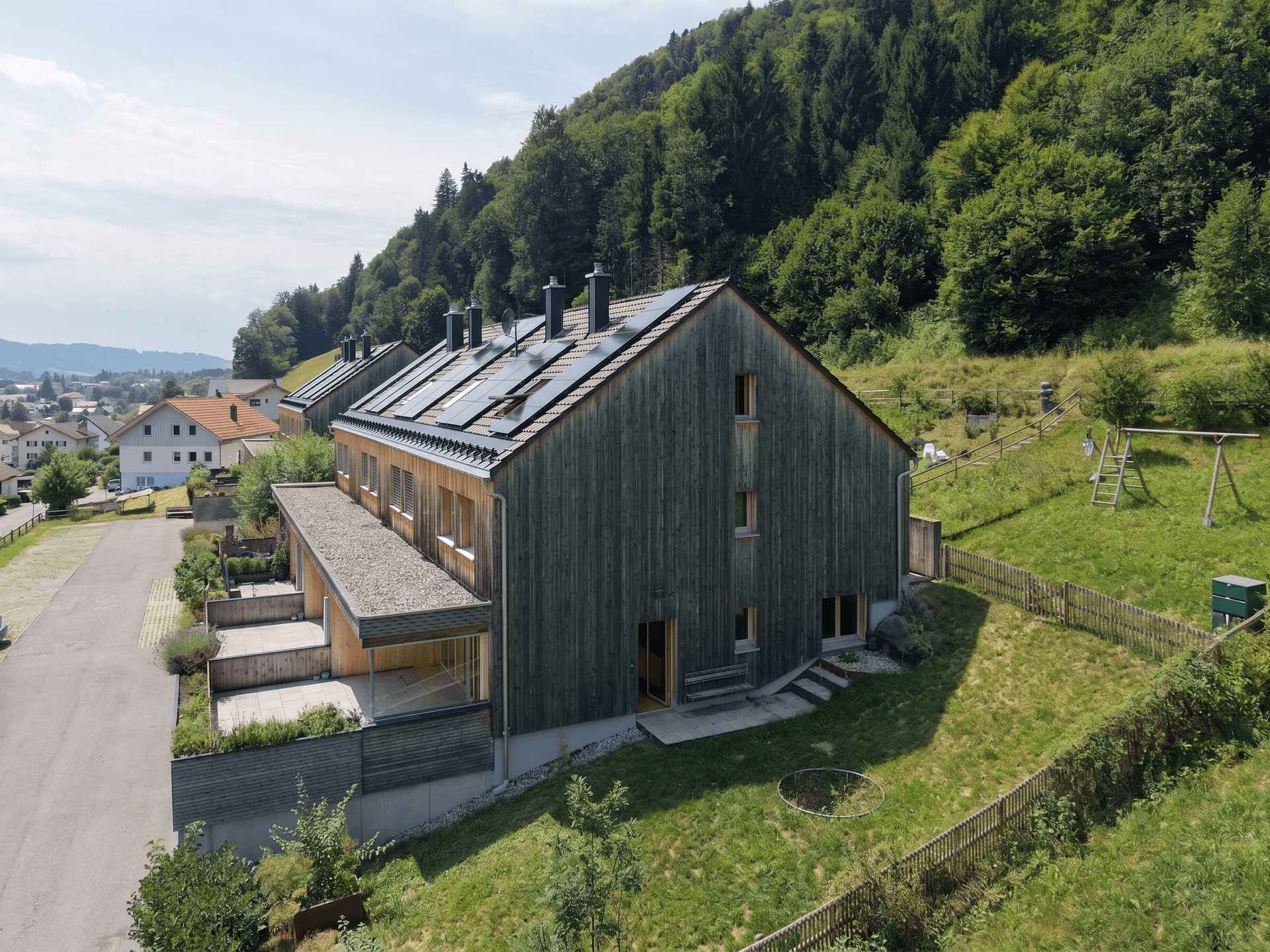 Moderne Reihenhäuser mit Holzfassade und Photovoltaikanlagen in ländlicher Umgebung.
