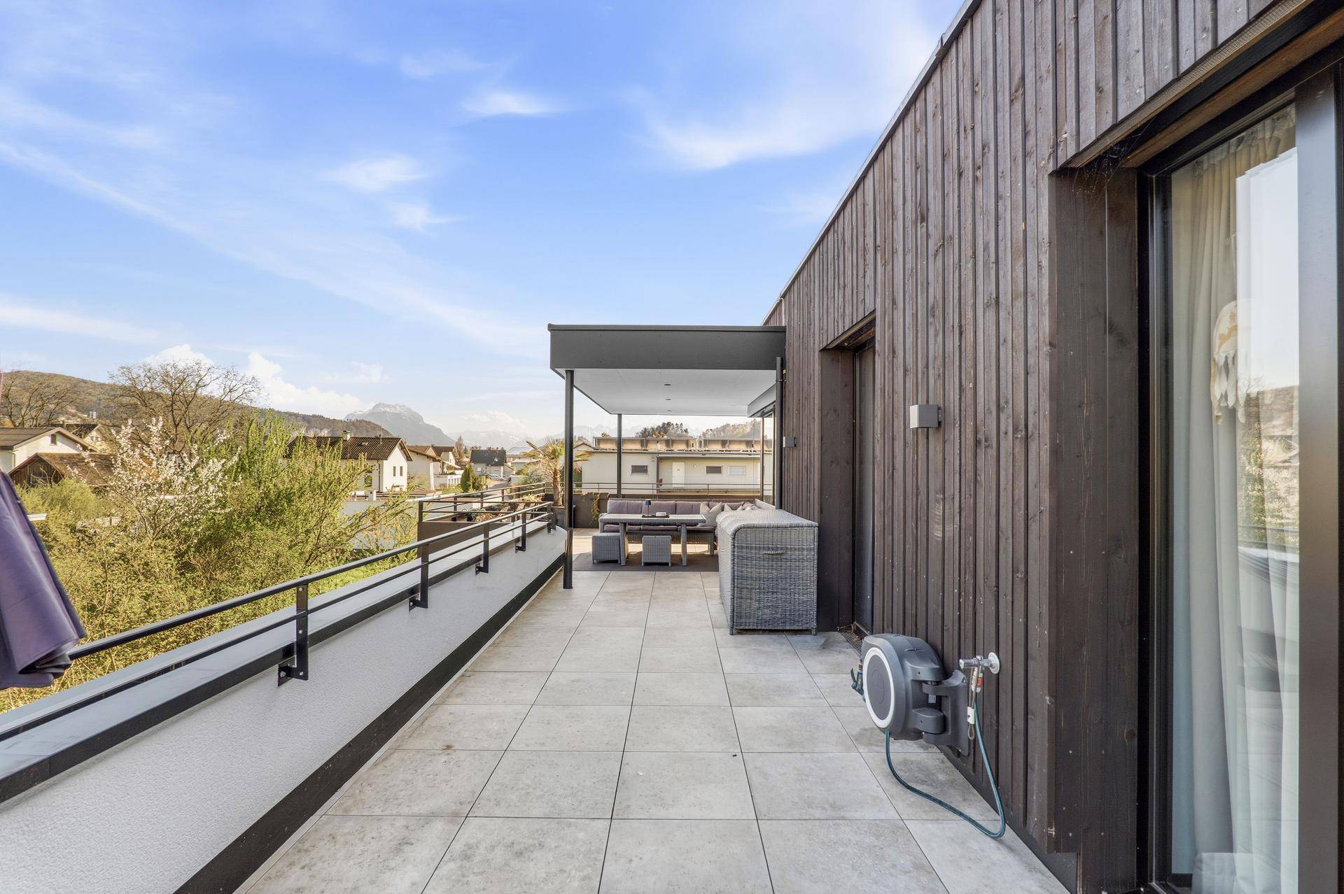 Weitläufige Terrasse mit Holzfassade und Blick auf die Umgebung.