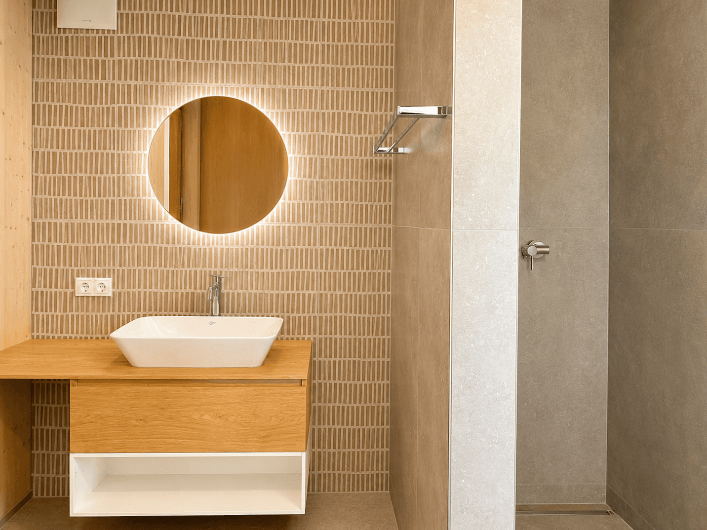 Modernes Badezimmer mit stilvollem Waschtisch, beleuchtetem Spiegel und ebenerdiger Dusche.