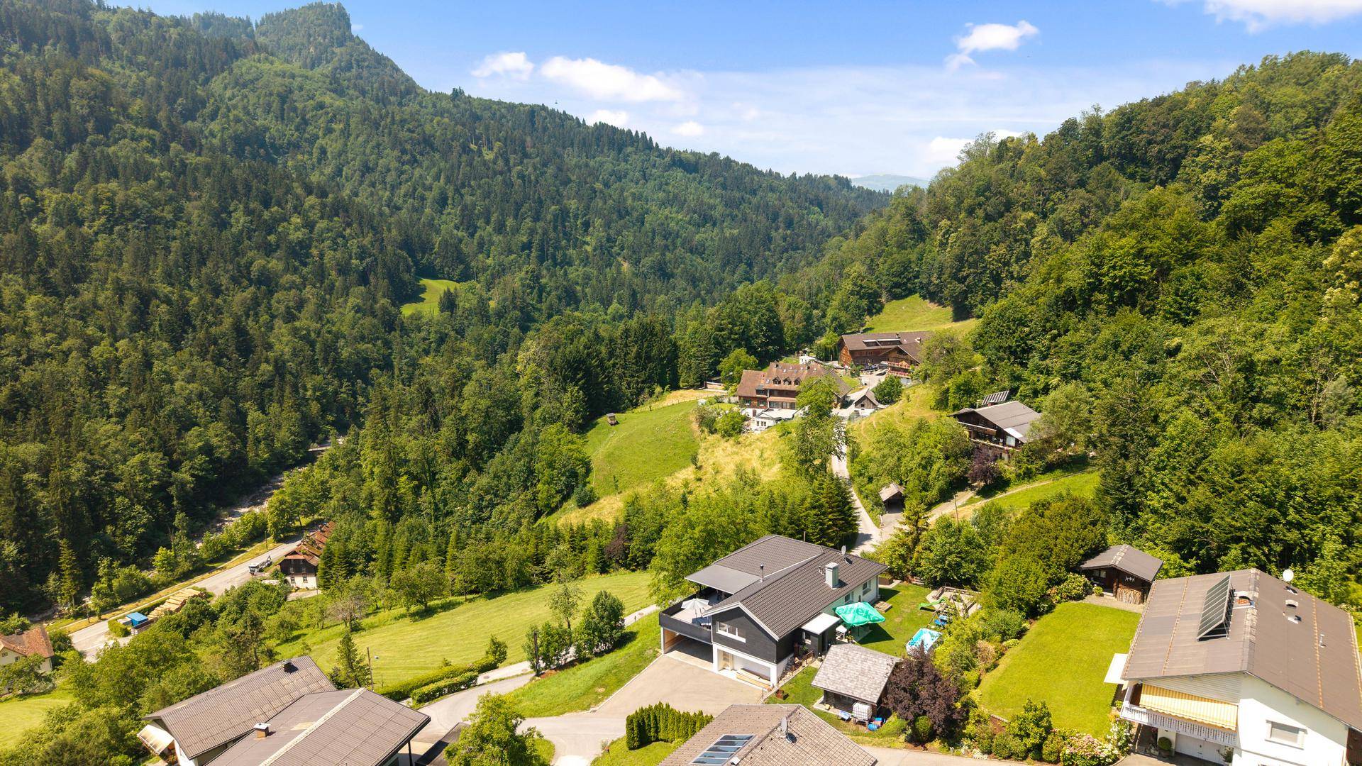 Weitläufige Luftaufnahme des Anwesens eingebettet in eine grüne Berglandschaft.
