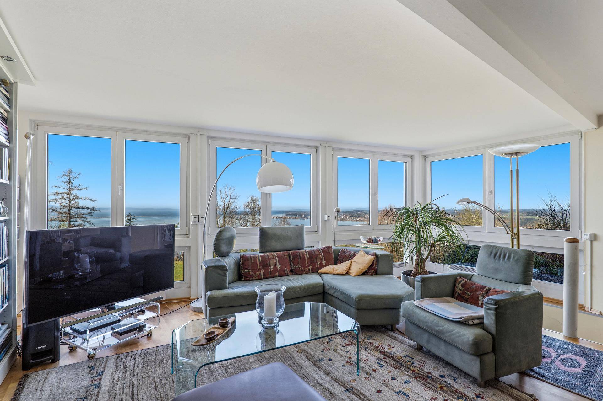Helles Wohnzimmer mit großen Fenstern, die einen weiten Blick auf den See bieten.