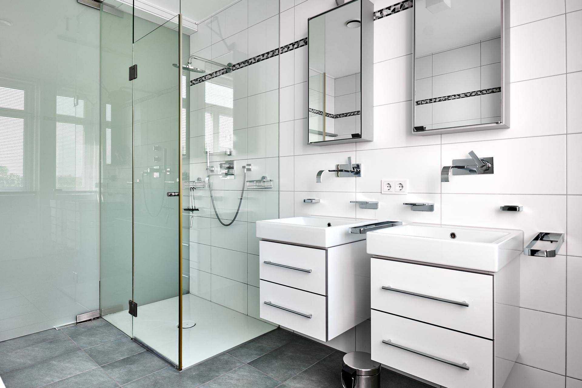 Helles Badezimmer mit begehbarer Dusche, Doppelwaschbecken und Spiegelschränken, in modernem Design.
