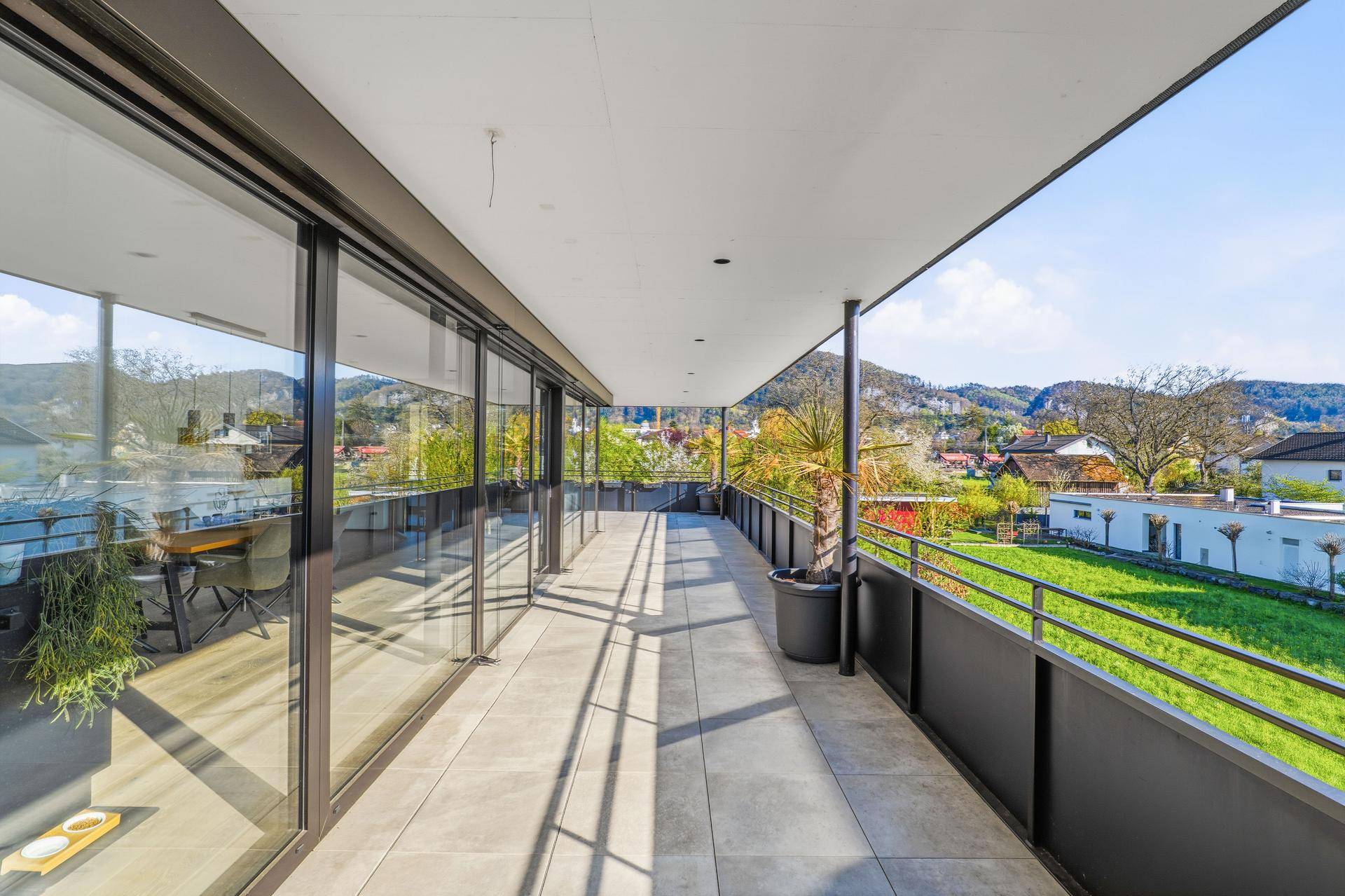 Geräumiger Balkon mit Glasfronten und Blick auf die grüne Umgebung.