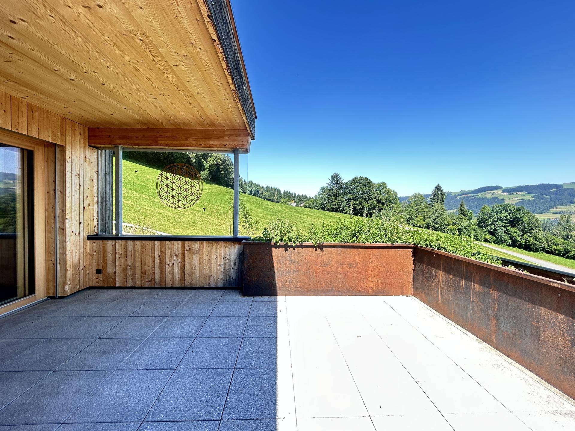 Große Sonnenterrasse mit Fliesenboden und beeindruckendem Panoramablick auf die Berge.