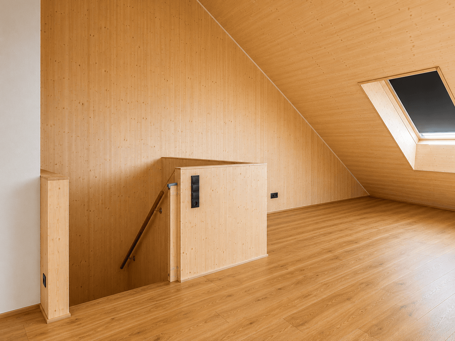 Heller Dachbodenraum mit Holzboden, Dachschräge und Dachfenster, ideal als Galerie.