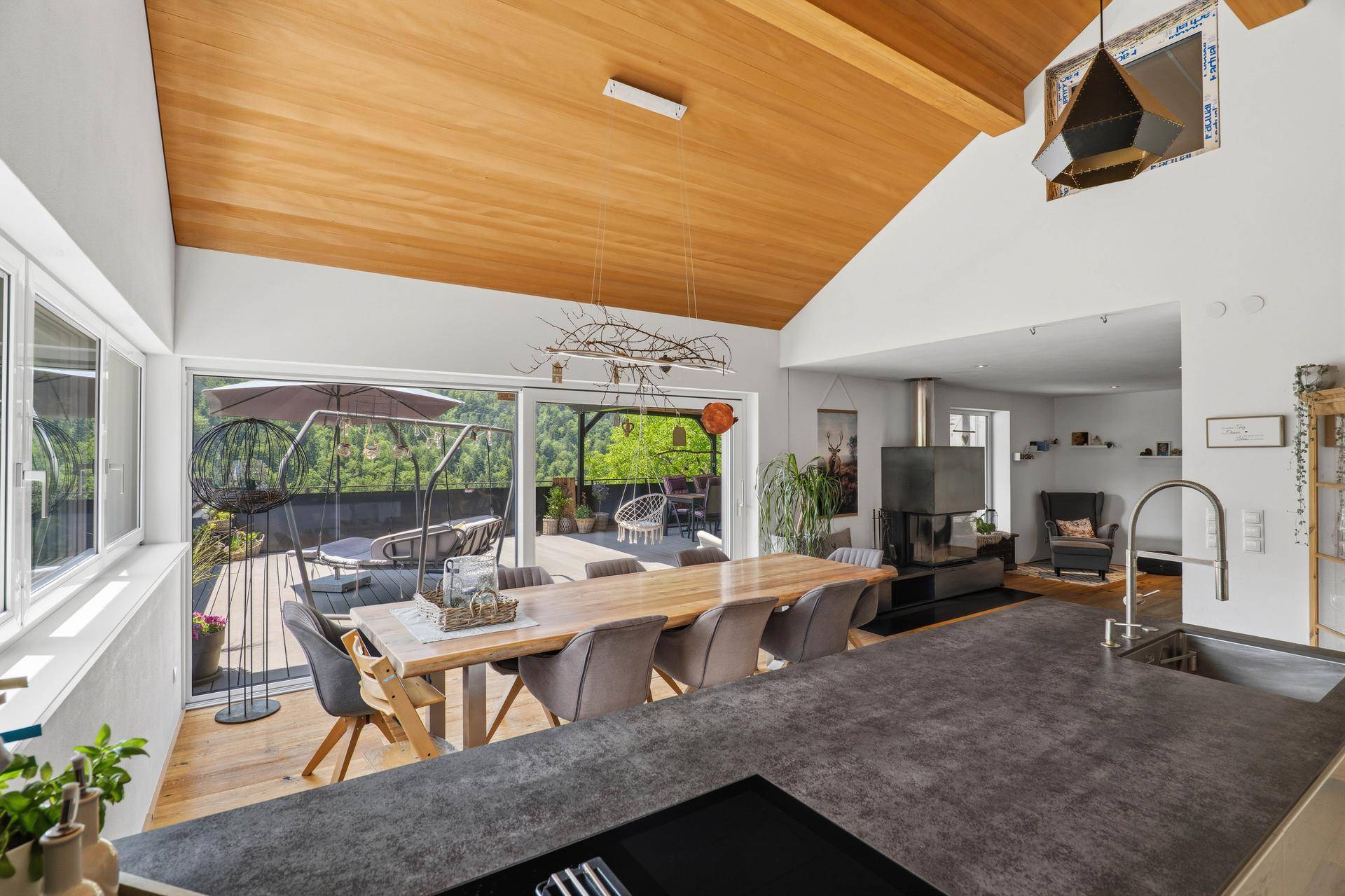 Heller Wohn-Essbereich mit offener Küche, Holzdachschräge und Terrassenzugang.