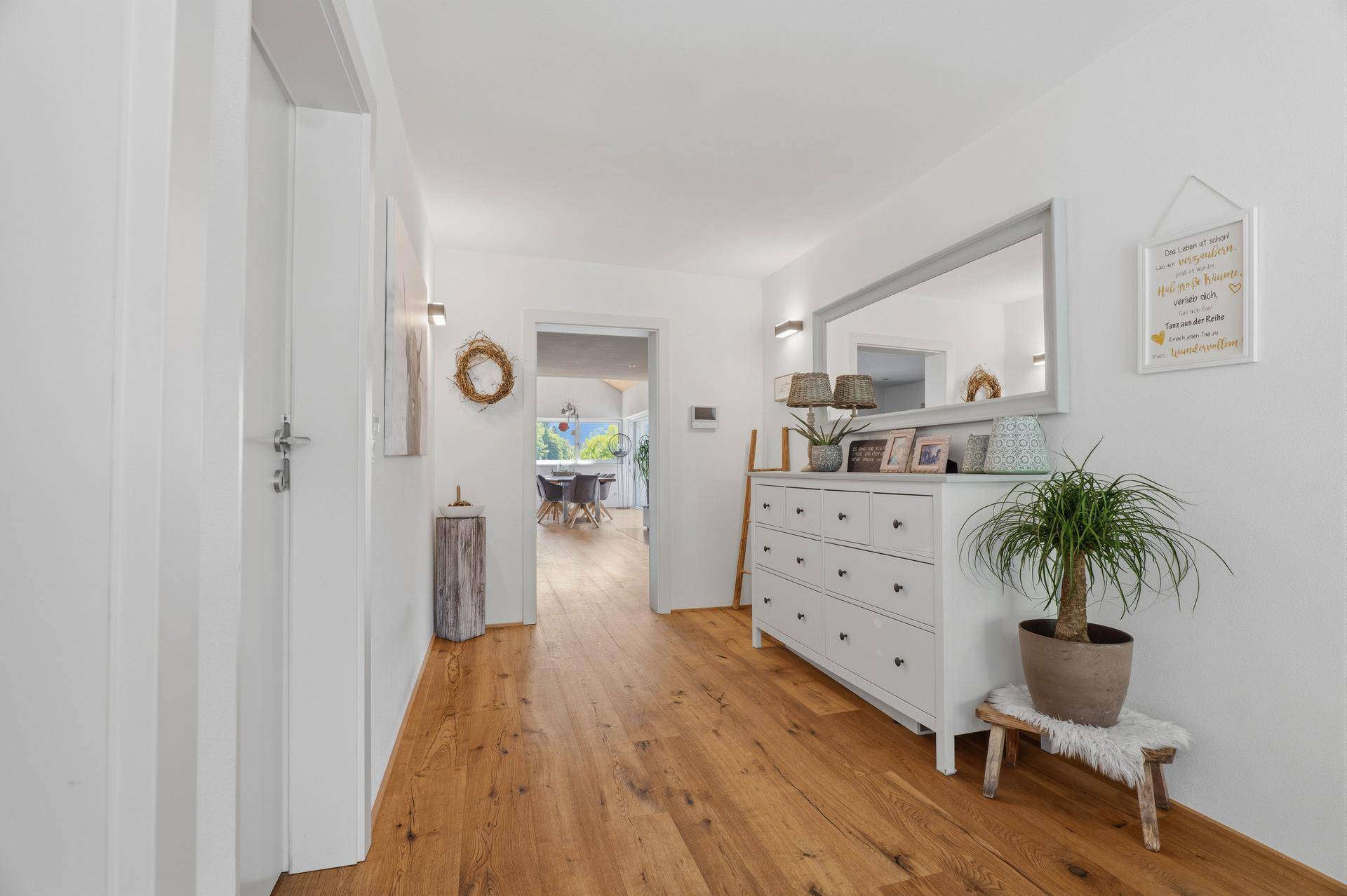 Geräumiger Flur mit Holzboden, Spiegel und dekorativen Pflanzen.