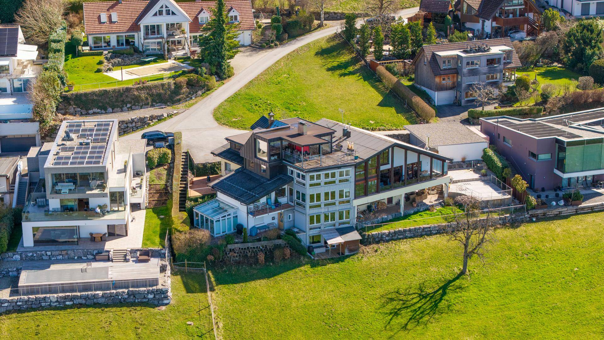 Luftaufnahme eines weitläufigen Anwesens mit moderner Architektur und umliegenden Grünflächen.