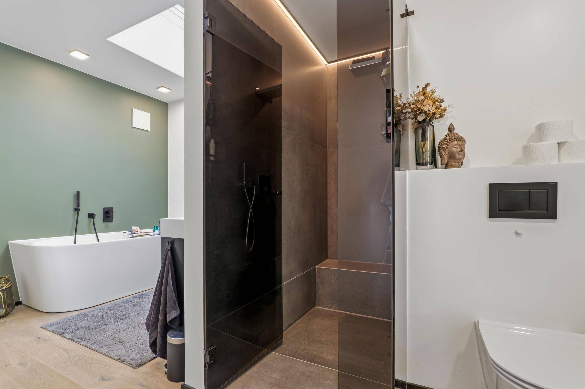Stilvolles Badezimmer mit großer begehbarer Dusche, freistehender Badewanne und Oberlicht.