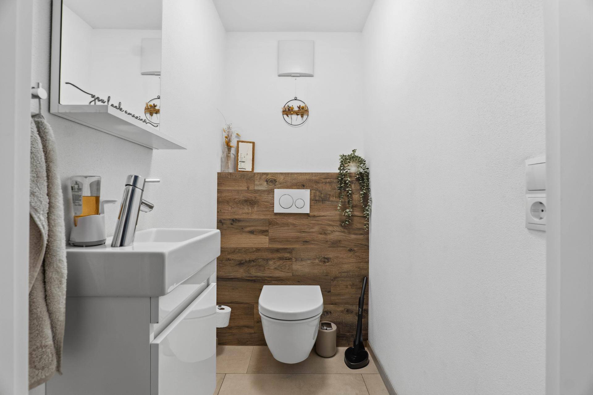 Modernes Gäste-WC mit Wand-WC, Waschbecken und Holzverkleidung.