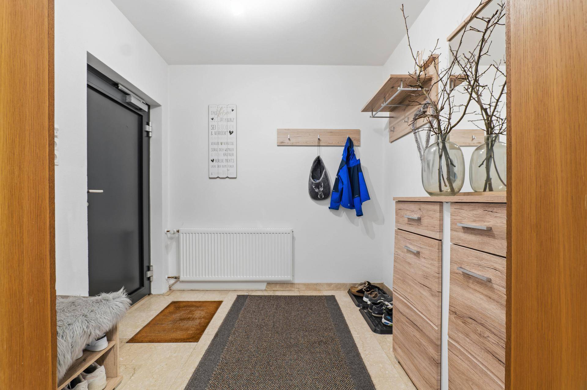 Heller Eingangsbereich mit Fliesenboden, Garderobe und Holzmöbeln.