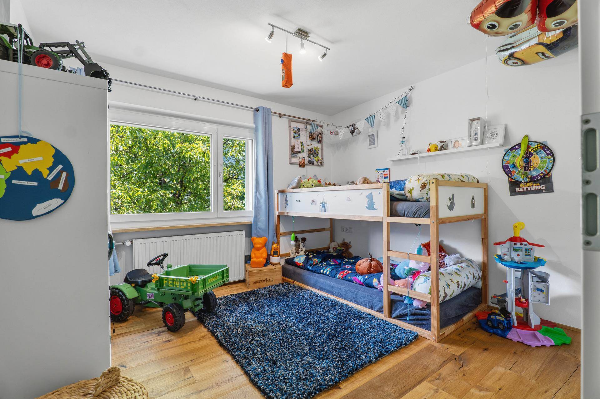 Kinderzimmer mit Etagenbett, Holzboden und Blick ins Grüne.