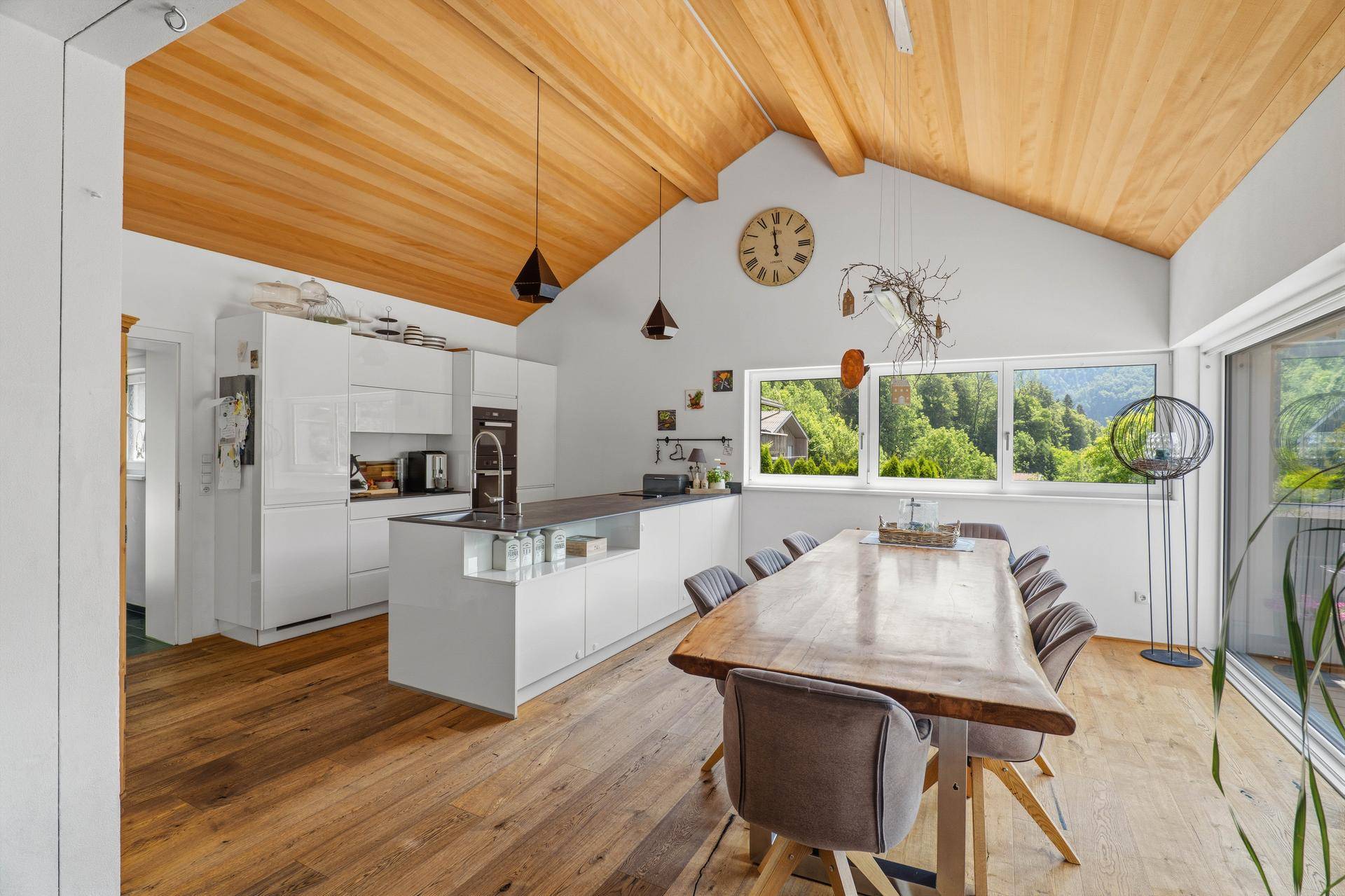 Offener Wohn-Essbereich mit Holzboden, Holzdachschräge und moderner Küche.
