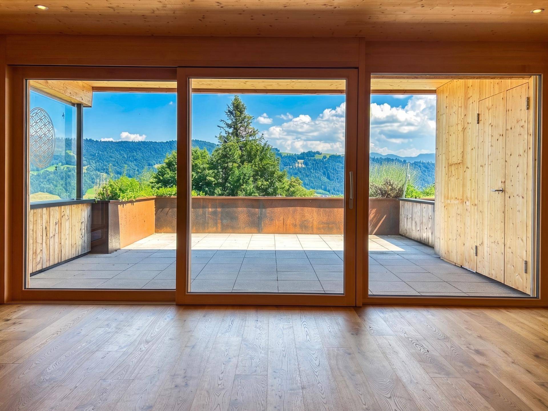 Lichtdurchfluteter Wohnbereich mit Zugang zur Terrasse und weitem Bergblick.