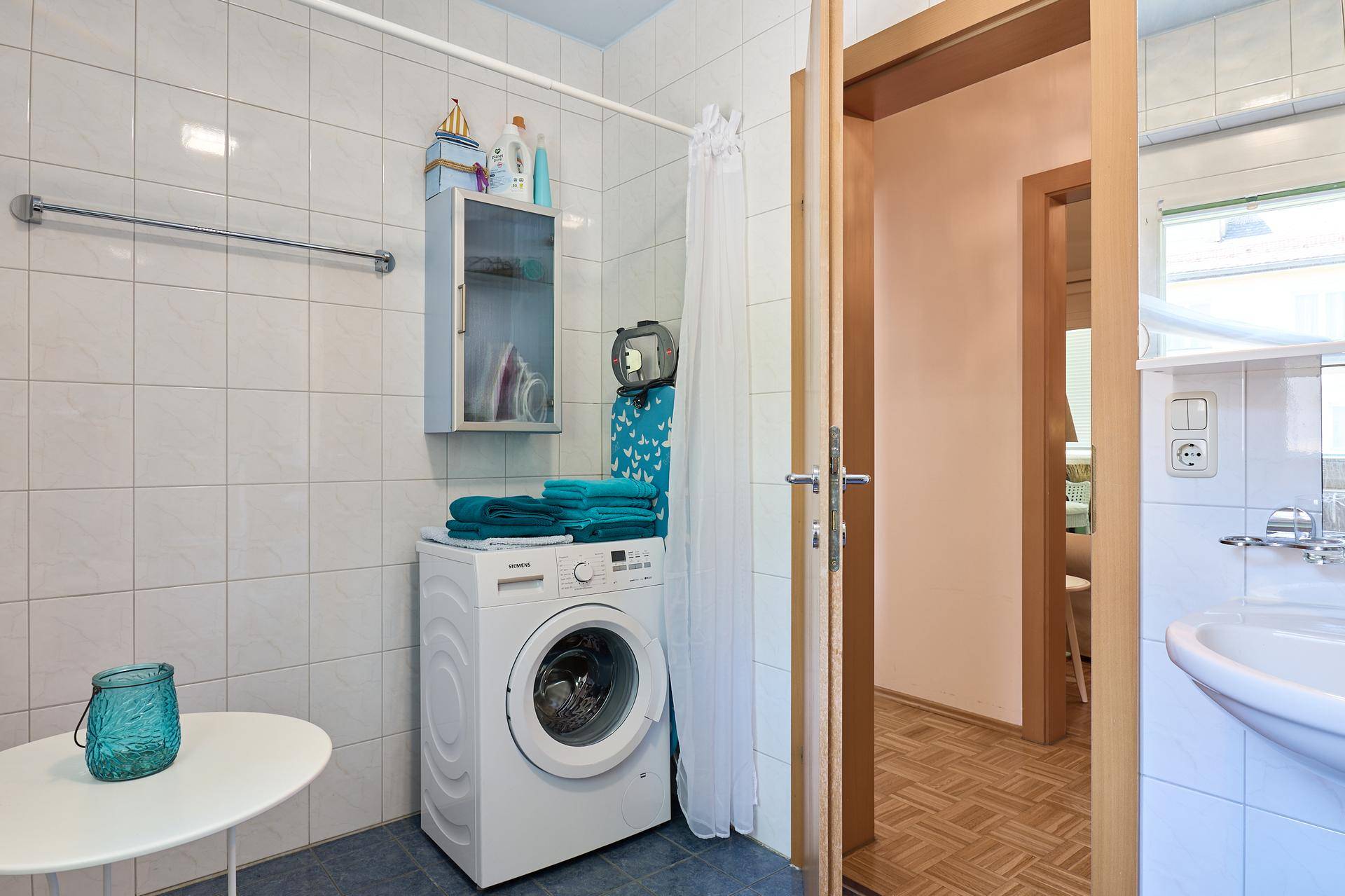 Praktischer Waschbereich im Badezimmer mit Waschmaschine und zusätzlichem Stauraum.