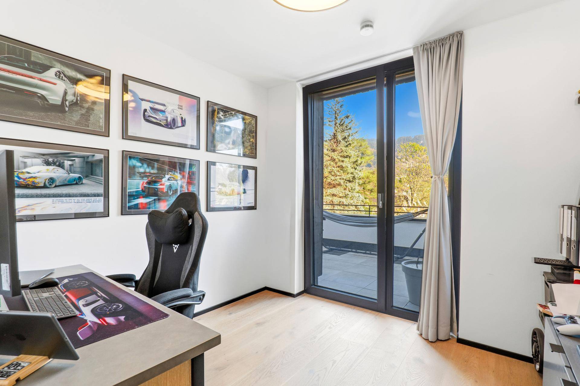 Modernes Arbeitszimmer mit Schreibtisch, Gaming-Stuhl und Zugang zur Terrasse.