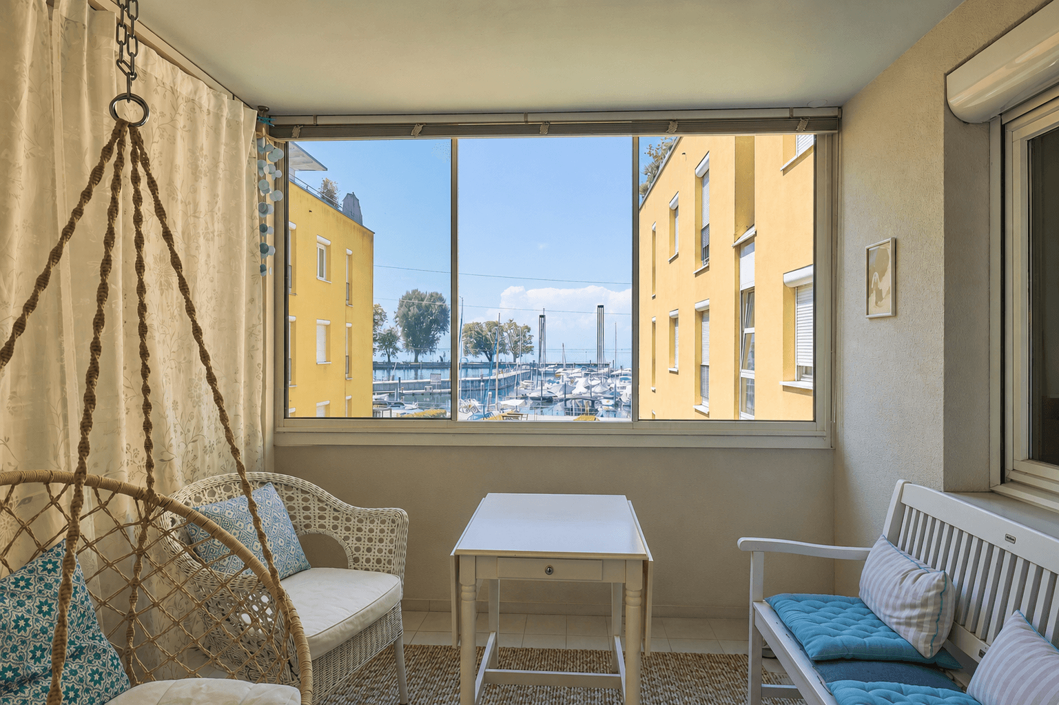 Verglaste Loggia mit gemütlichen Sitzgelegenheiten und herrlichem Blick auf den Yachthafen und den See.