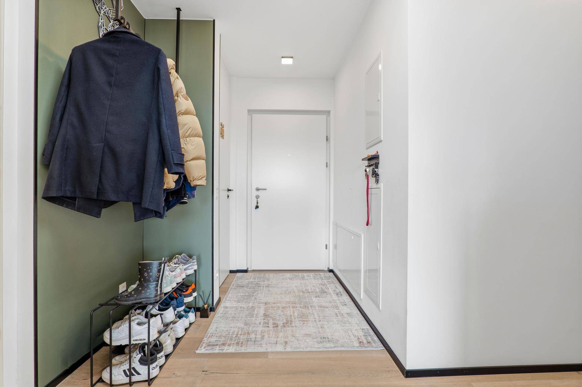 Heller Eingangsbereich mit Garderobe, Schuhregal und Holzboden.