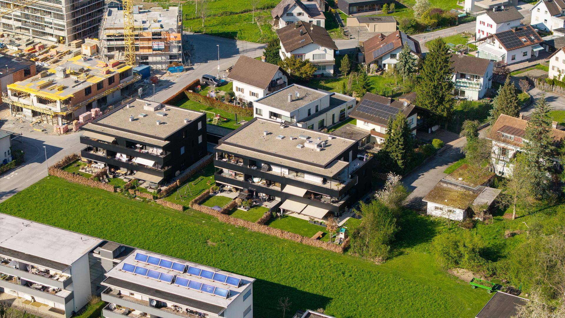 Luftaufnahme von modernen Wohngebäuden in einer grünen Umgebung mit Baustelle.