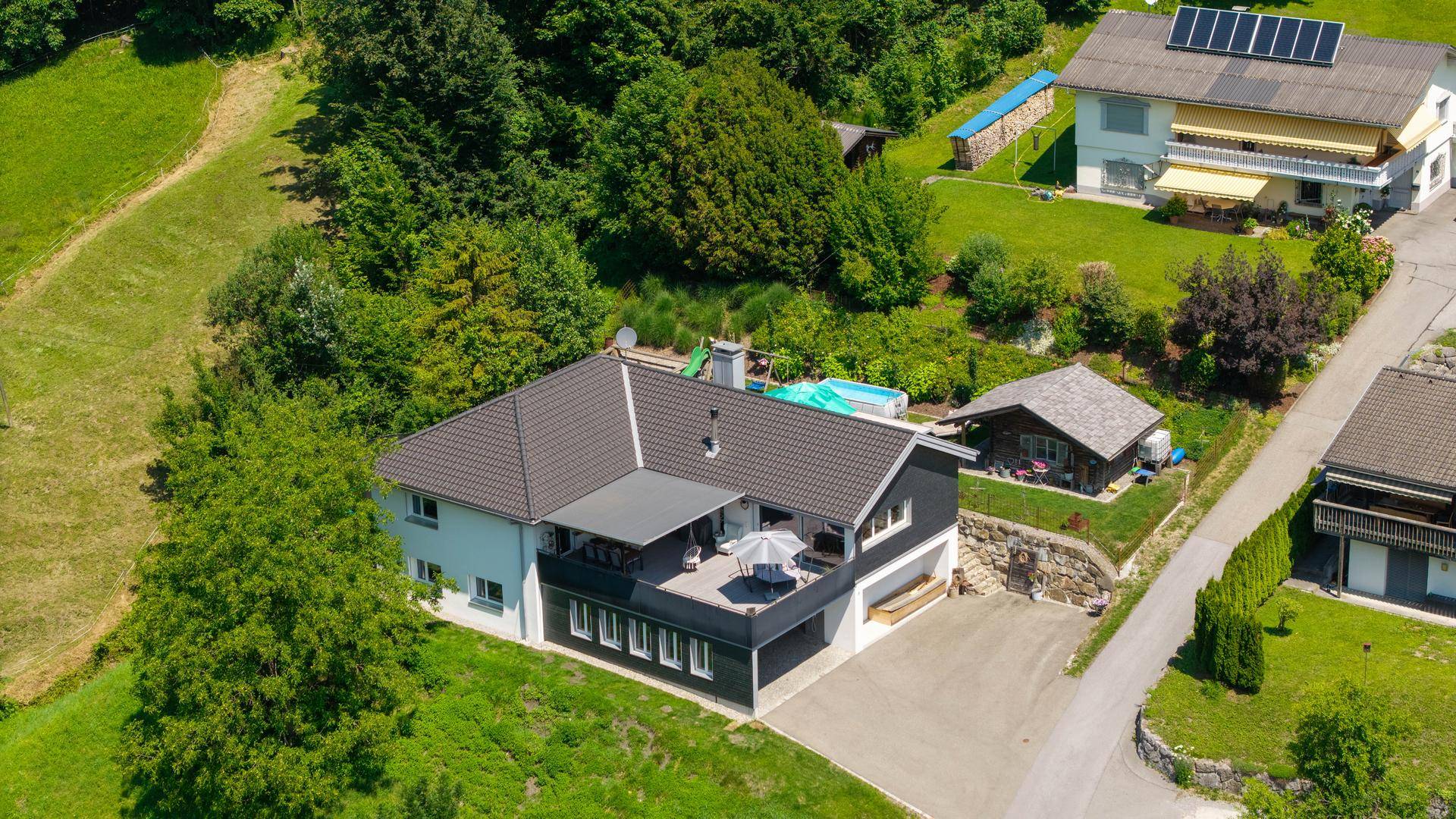 Ansicht des Hauses von oben mit Terrasse, Garten, Pool und Spielbereich.