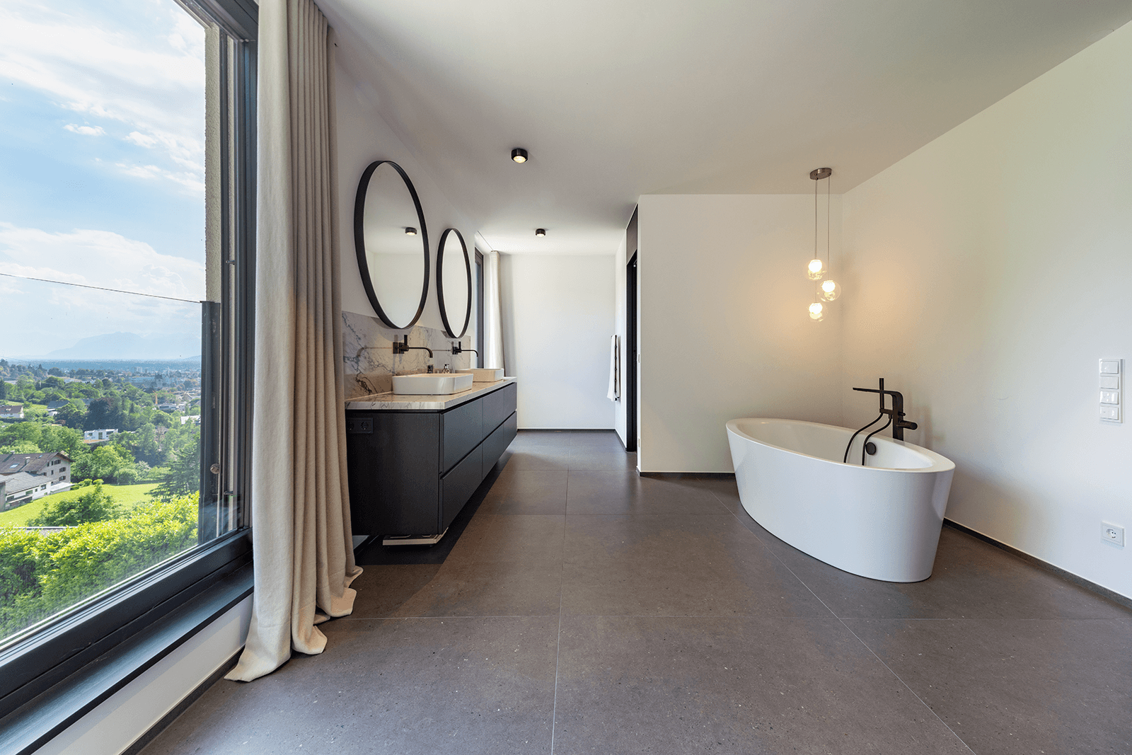 Modernes Badezimmer mit freistehender Badewanne, Doppelwaschbecken und großen Fenstern.