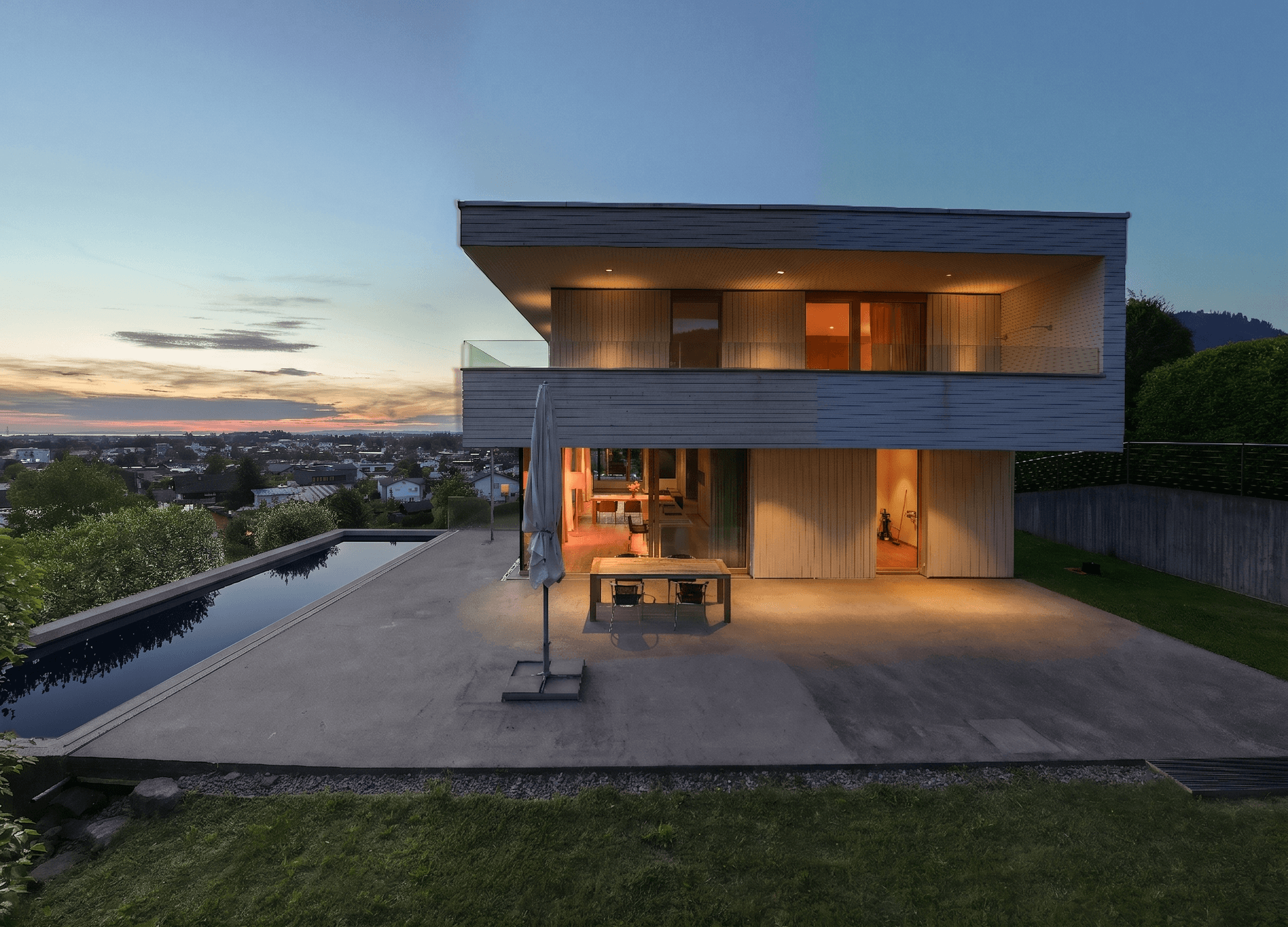 Beleuchtete moderne Villa bei Sonnenuntergang mit Infinity-Pool und großzügiger Terrasse.