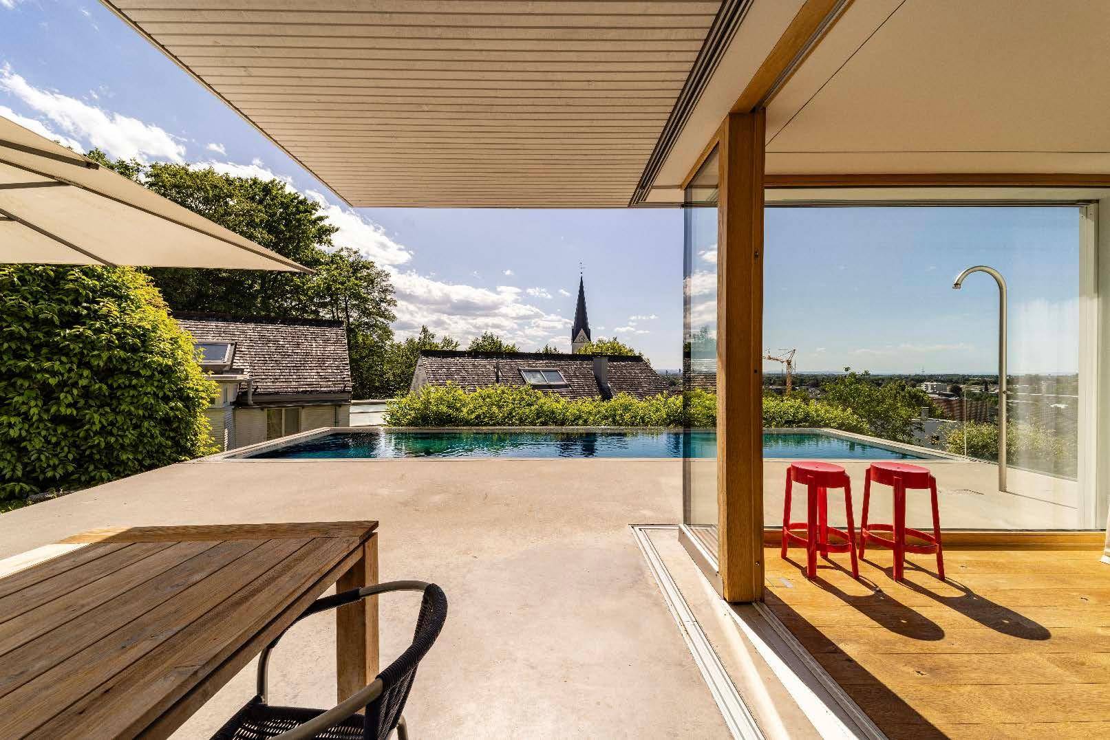 Sonniger Terrassenbereich mit Esstisch und Blick auf den Pool sowie die umliegende Landschaft.
