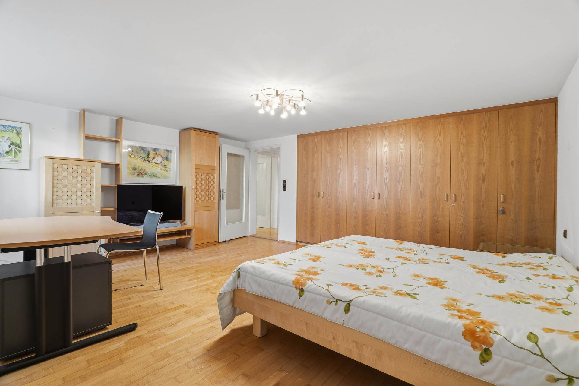 Schlafzimmer mit Holzboden, Einbauschränken und einem praktischen Arbeitsbereich.