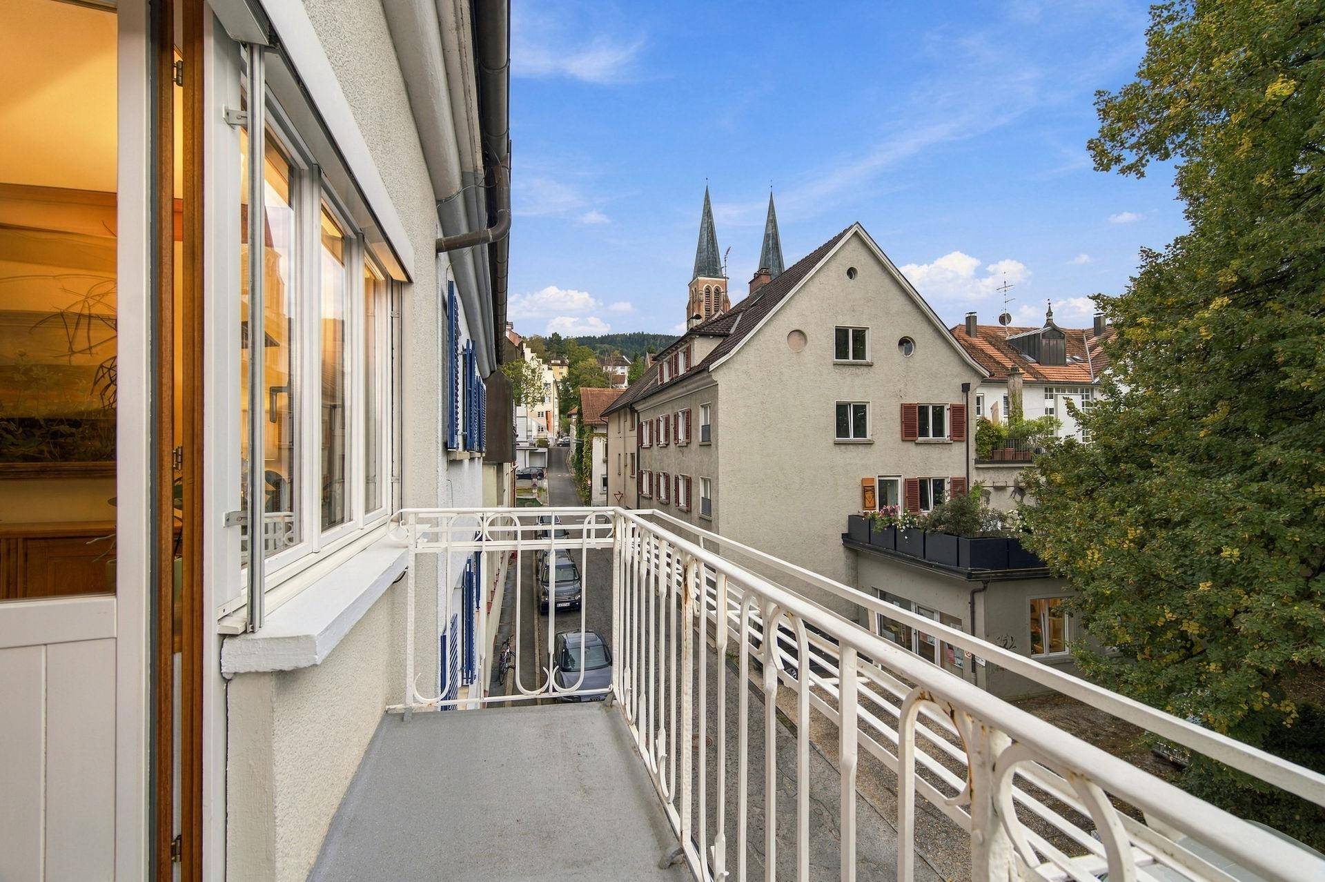 Balkon mit Blick auf eine ruhige Straße und die Kirchtürme der Stadt.