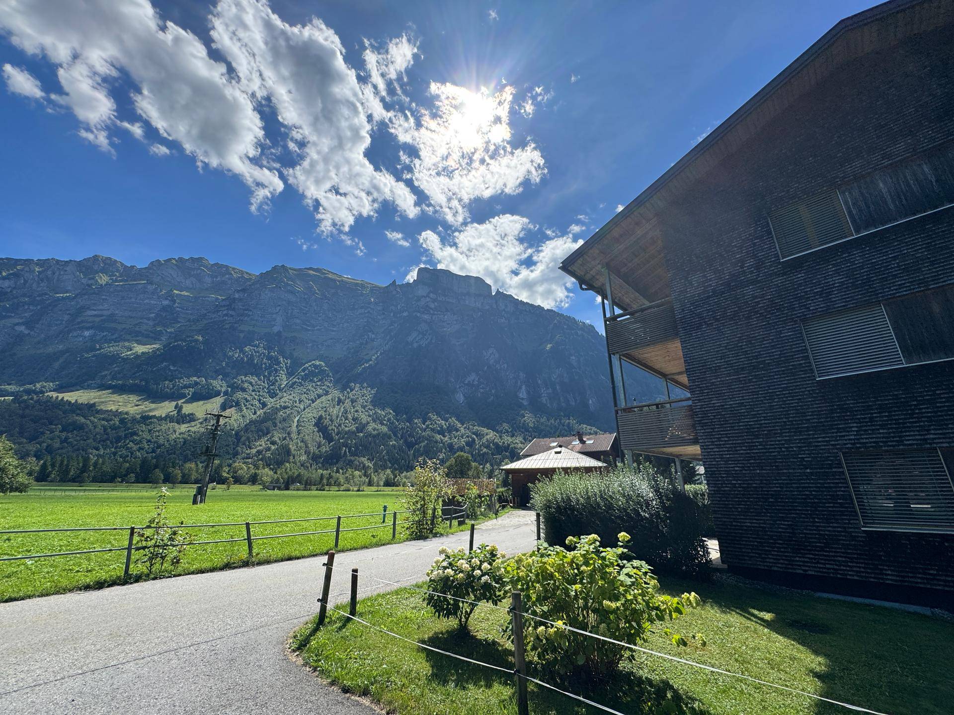 Malerische Landschaft mit majestätischen Bergen und weiten grünen Feldern unter strahlend blauem Himmel.