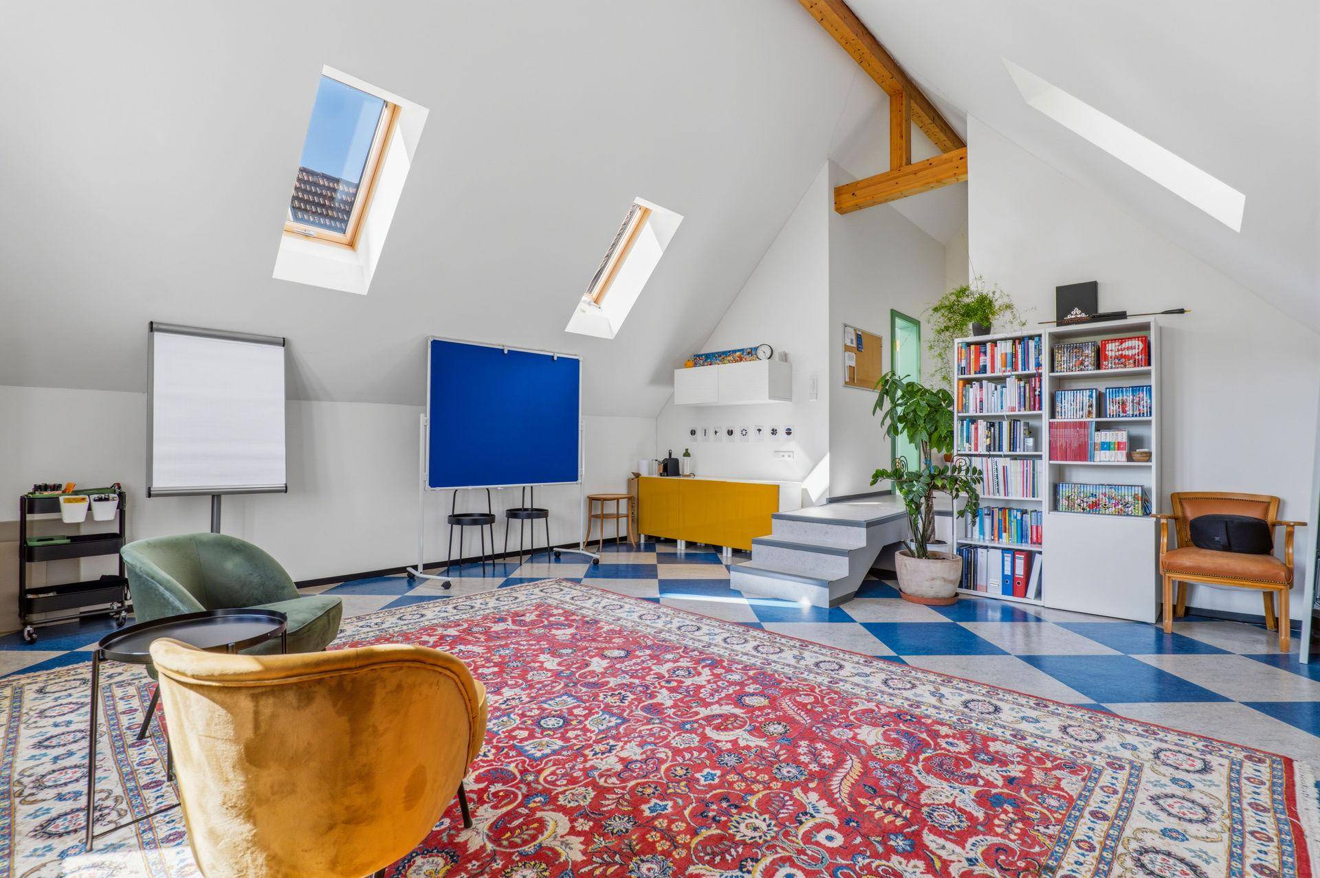 Geräumiger Dachbodenraum mit Schrägdach, Dachfenstern und farbenfrohem Fliesenboden, ideal als Büro.