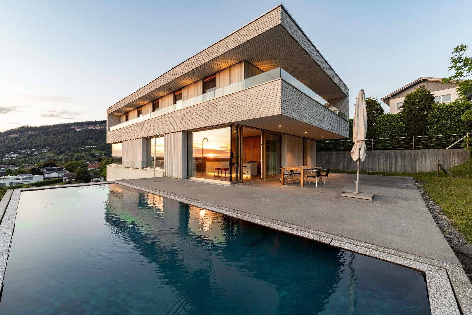 Moderne Architektur einer Villa mit großzügigen Glasfronten und einem Infinity-Pool im Vordergrund.