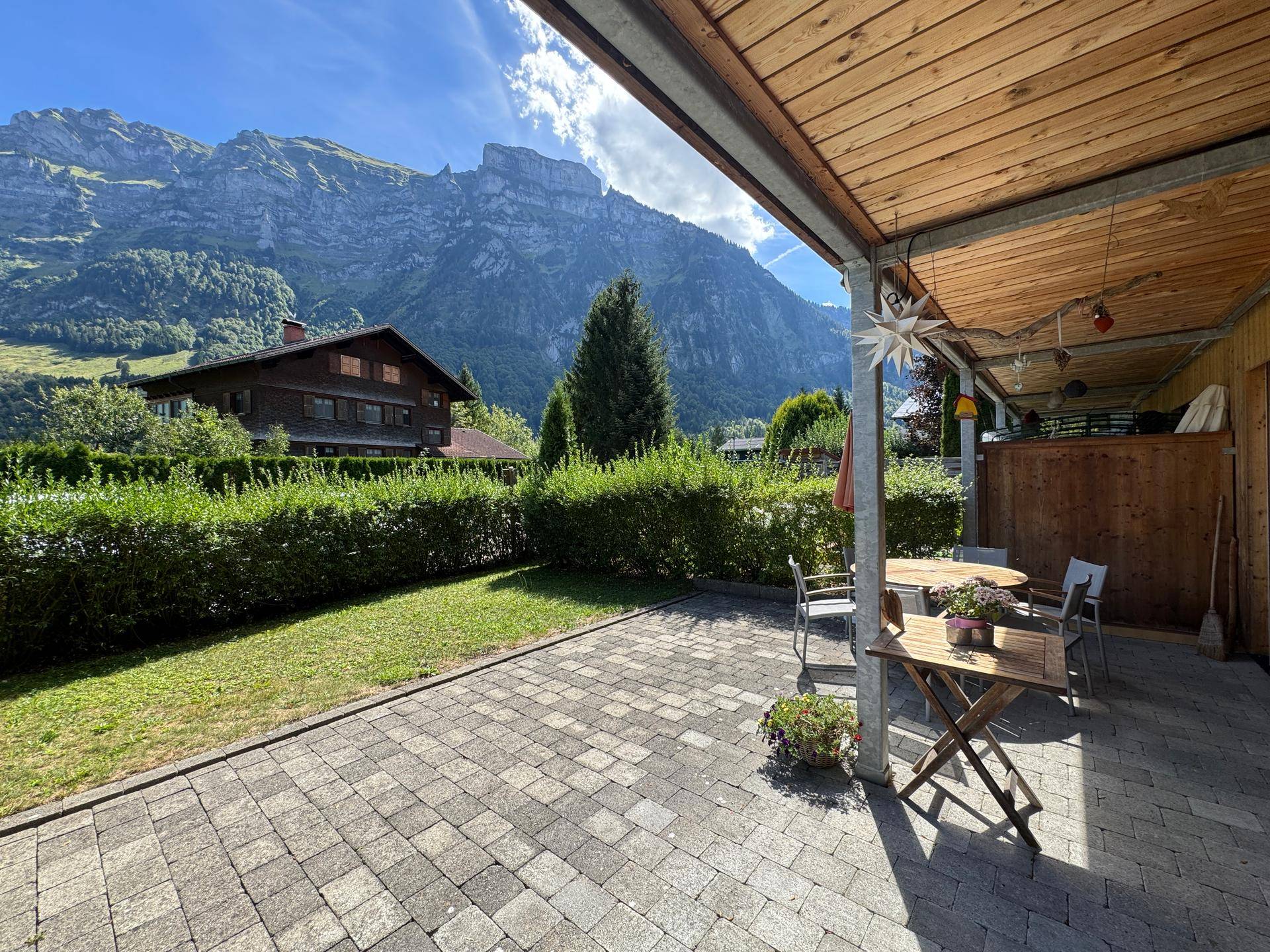 Geräumige Terrasse mit Bergblick, umgeben von Grünflächen und mit bequemen Sitzgelegenheiten.