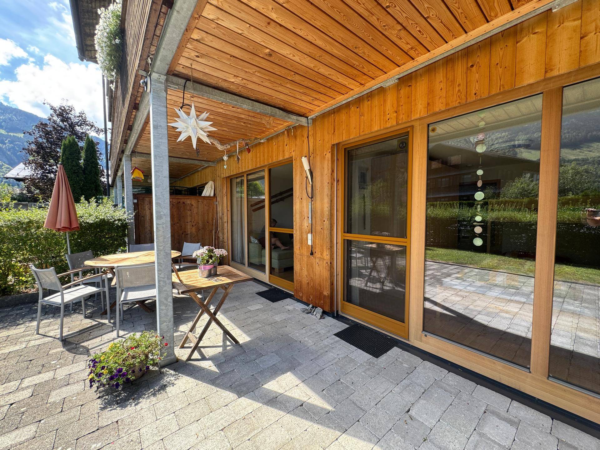 Überdachte Terrasse mit Sitzgelegenheiten und direktem Zugang zum Gebäude, ideal für Entspannung im Freien.