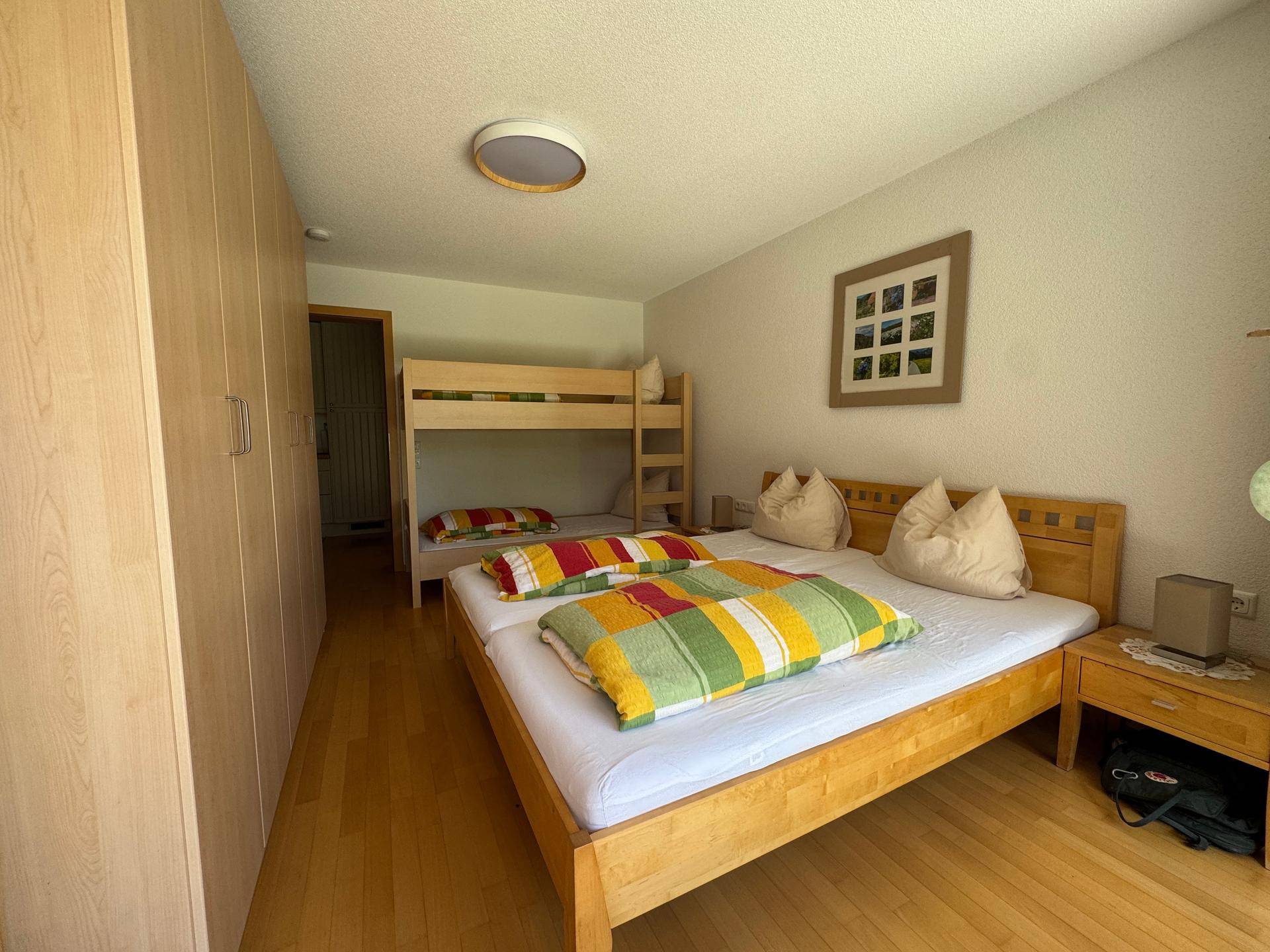 Geräumiges Schlafzimmer mit Doppelbett, Etagenbett und praktischen Einbauschränken.