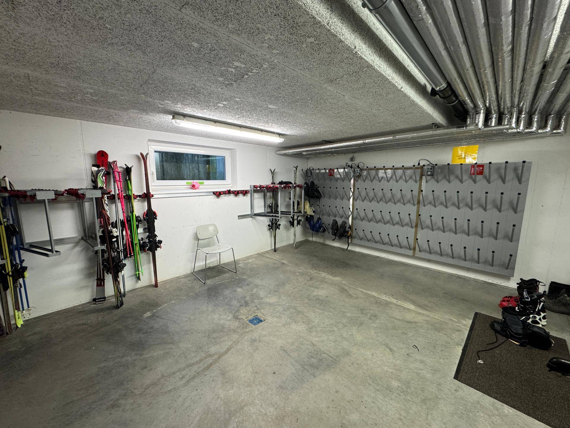 Geräumiger Skiraum im Keller mit praktischen Halterungen für Skier und Skischuhe.