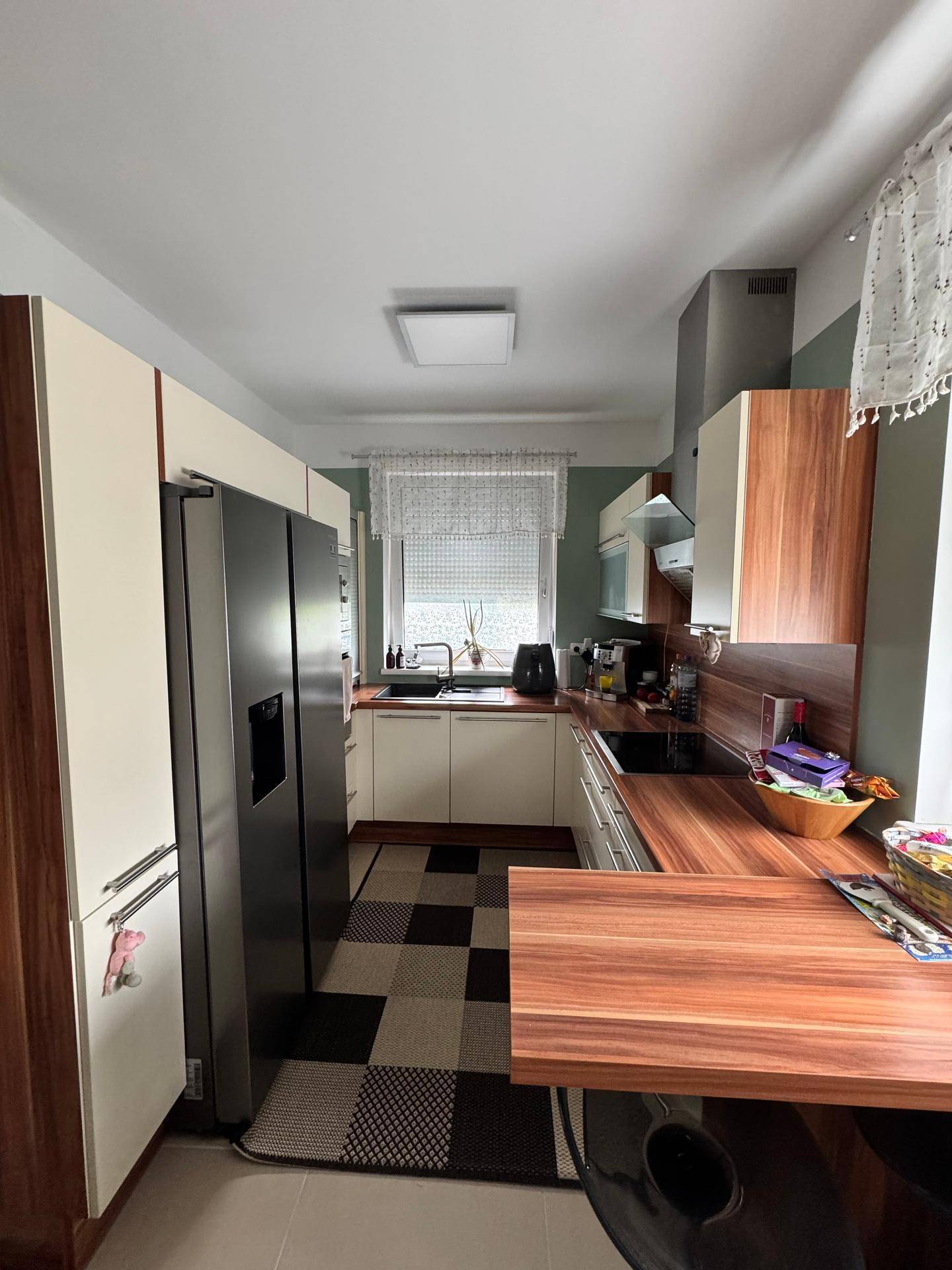 Moderne Küche mit Einbaugeräten, Holz-Arbeitsplatte und Kühlschrank, ideal für den täglichen Gebrauch.