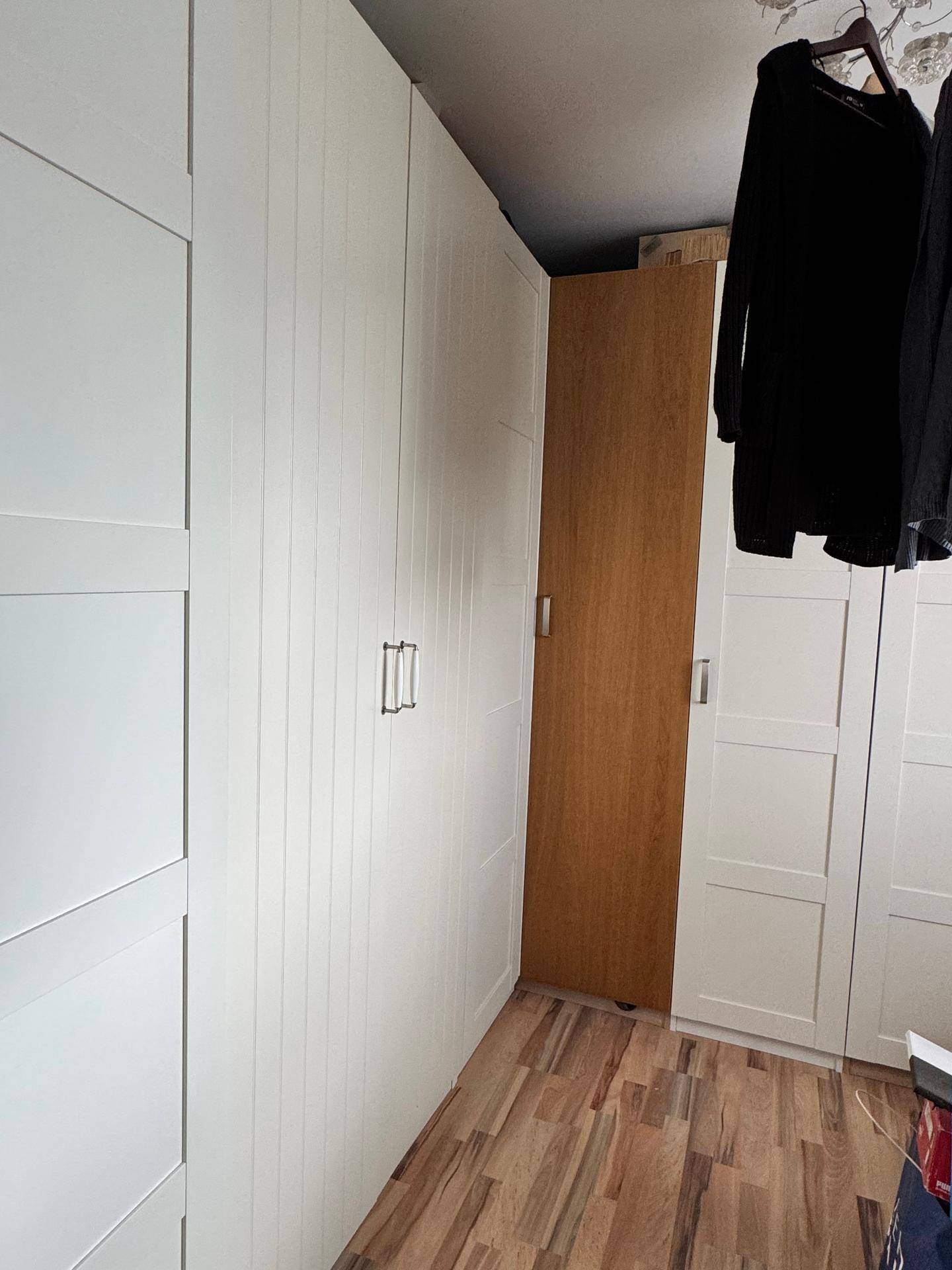 Schlafzimmer mit weißen Einbauschränken und Holzfußboden, bietet viel Stauraum und Helligkeit.
