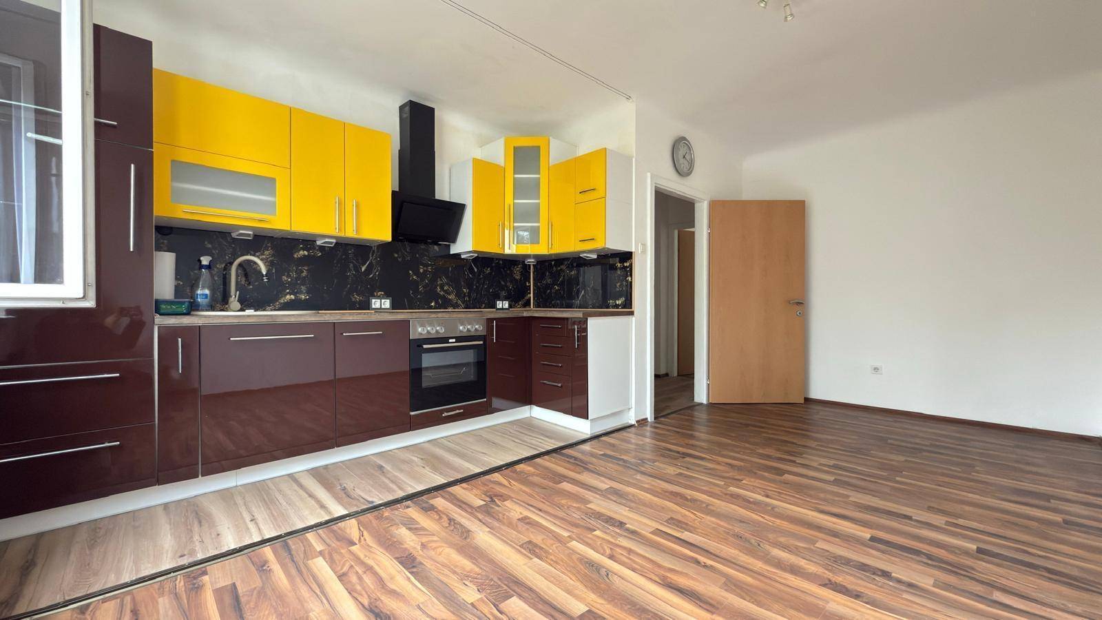 Geräumige Küche mit gelben und braunen Schränken, dunkler Arbeitsplatte und Holzboden.