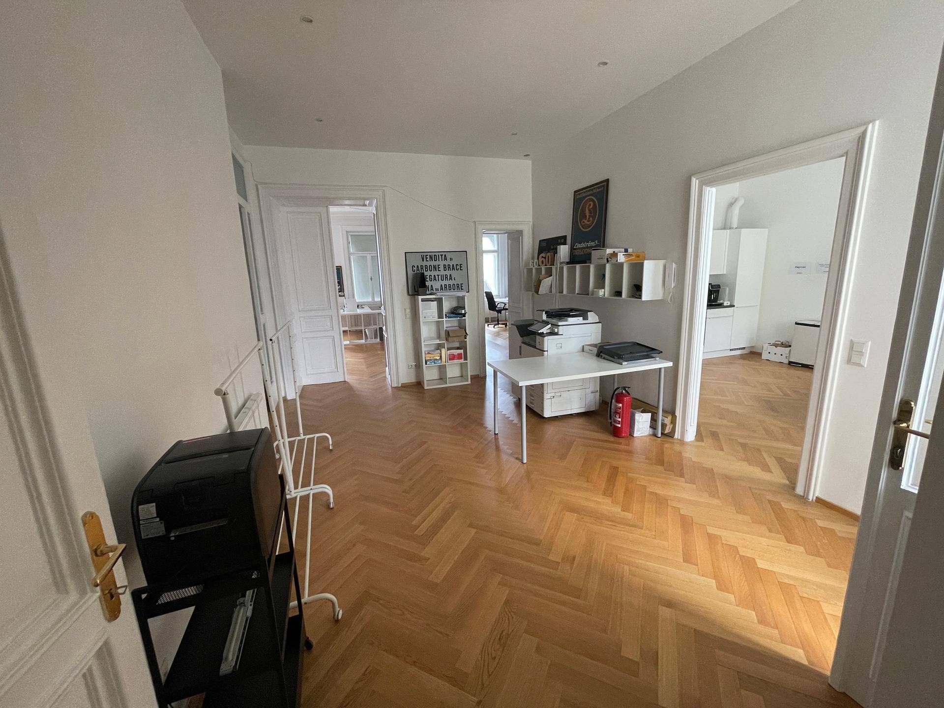 Langer Flur mit Holzboden, der verschiedene Büroräume und die Küche miteinander verbindet.