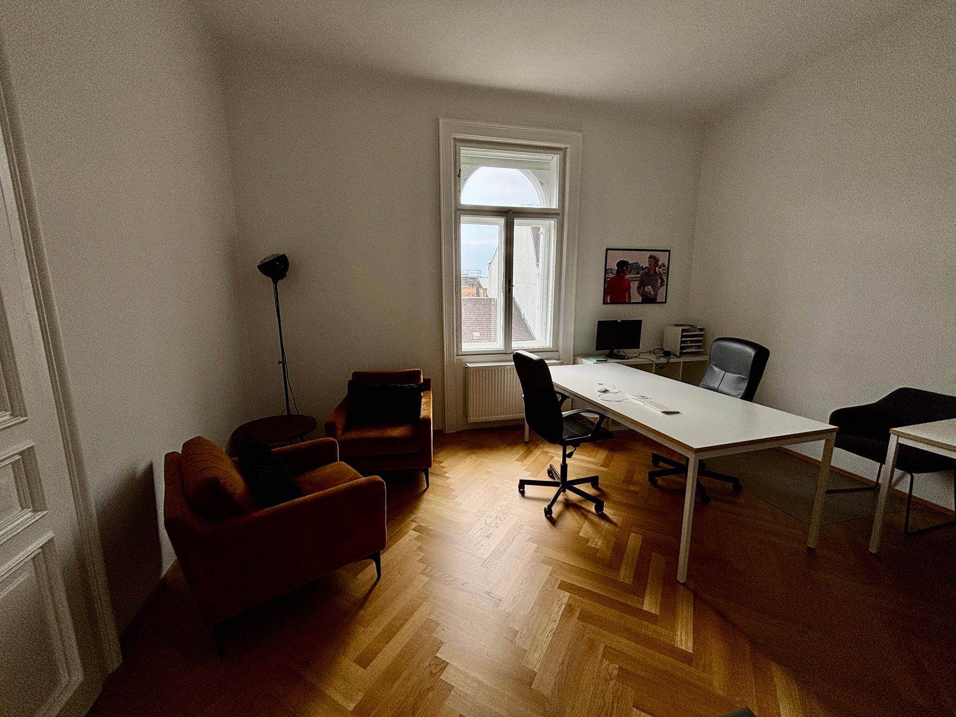 Ruhiges Einzelbüro mit Schreibtisch, zwei bequemen Sesseln und einem großen Fenster für viel Tageslicht.