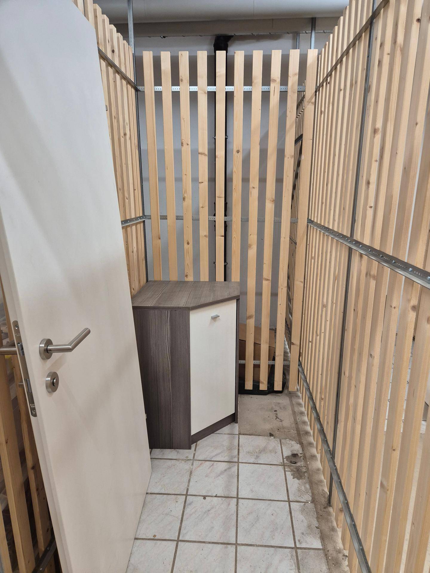 Kellerabteil mit Holzlattenwänden und Fliesenboden, bietet zusätzlichen Stauraum im Untergeschoss.