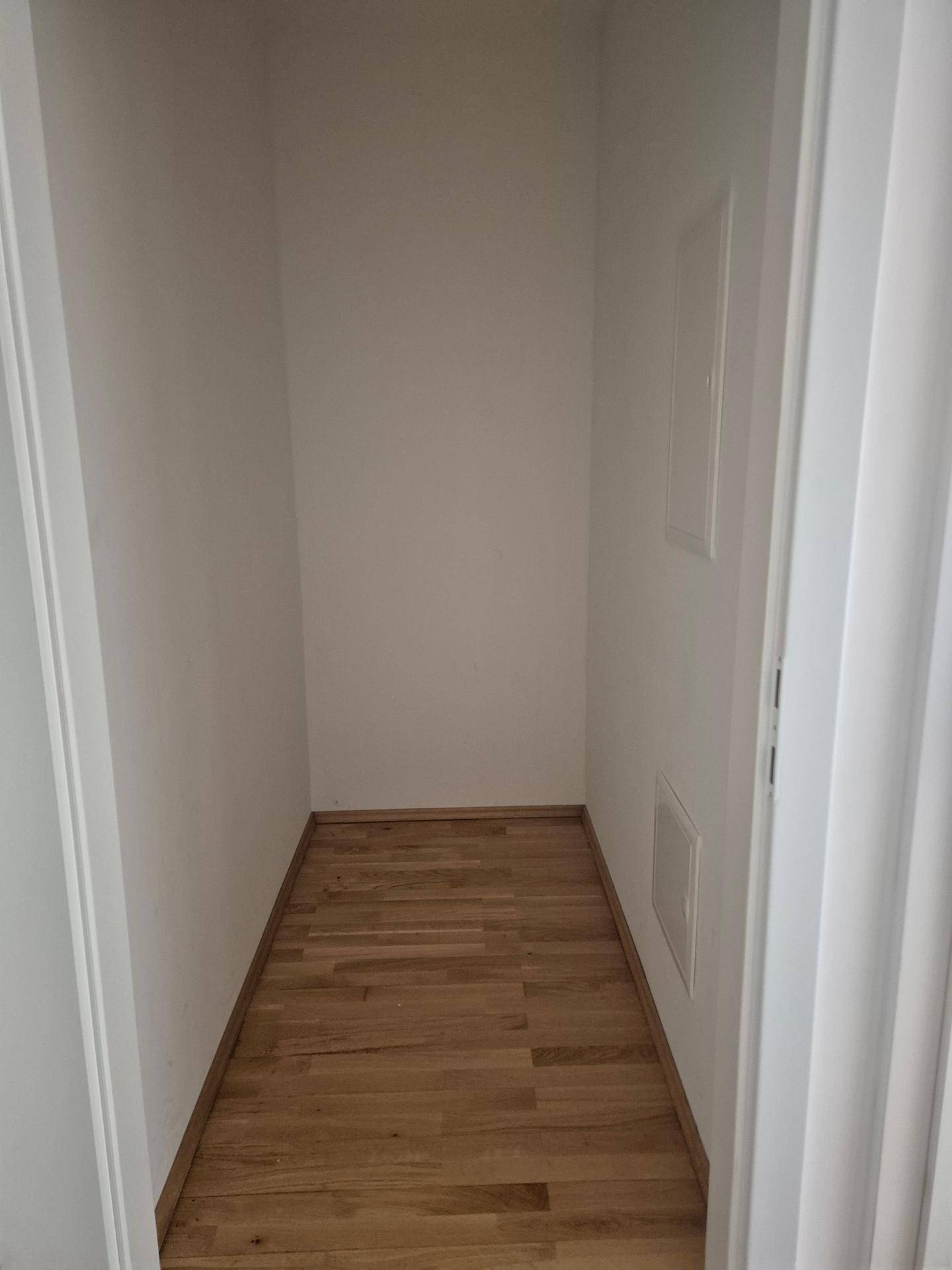 Praktischer Abstellraum mit Parkettboden und weißen Wänden für zusätzlichen Stauraum.