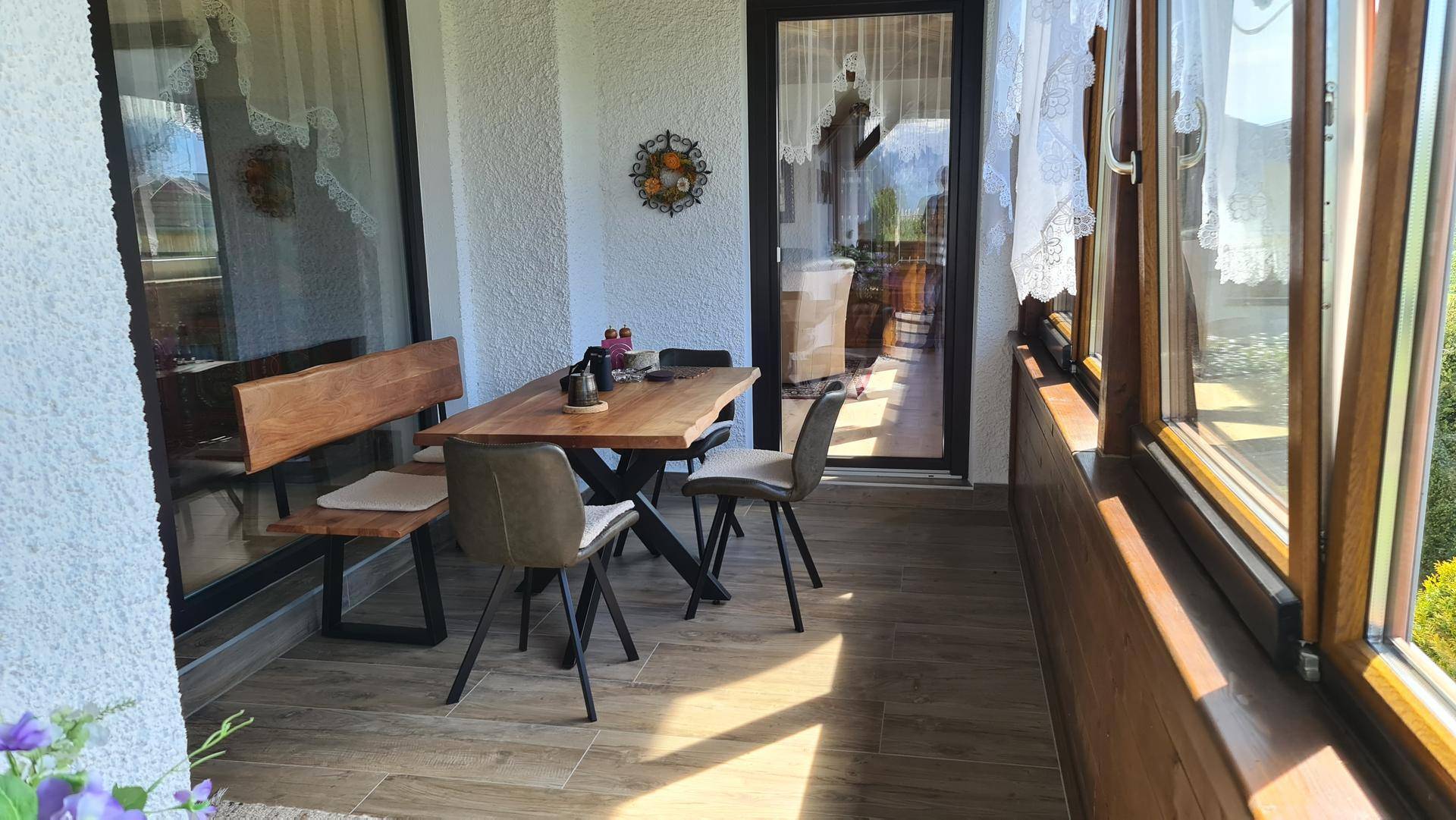 Gemütliche Loggia mit Holztisch und Stühlen, ideal für entspannte Stunden im Freien.