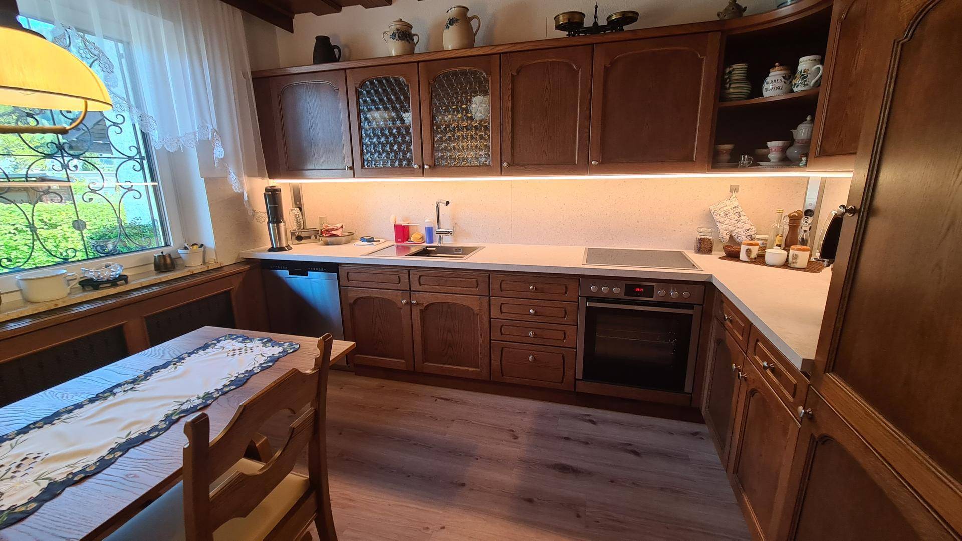 Traditionelle Holzküche mit modernen Geräten, hellem Arbeitsbereich und integriertem Essplatz.