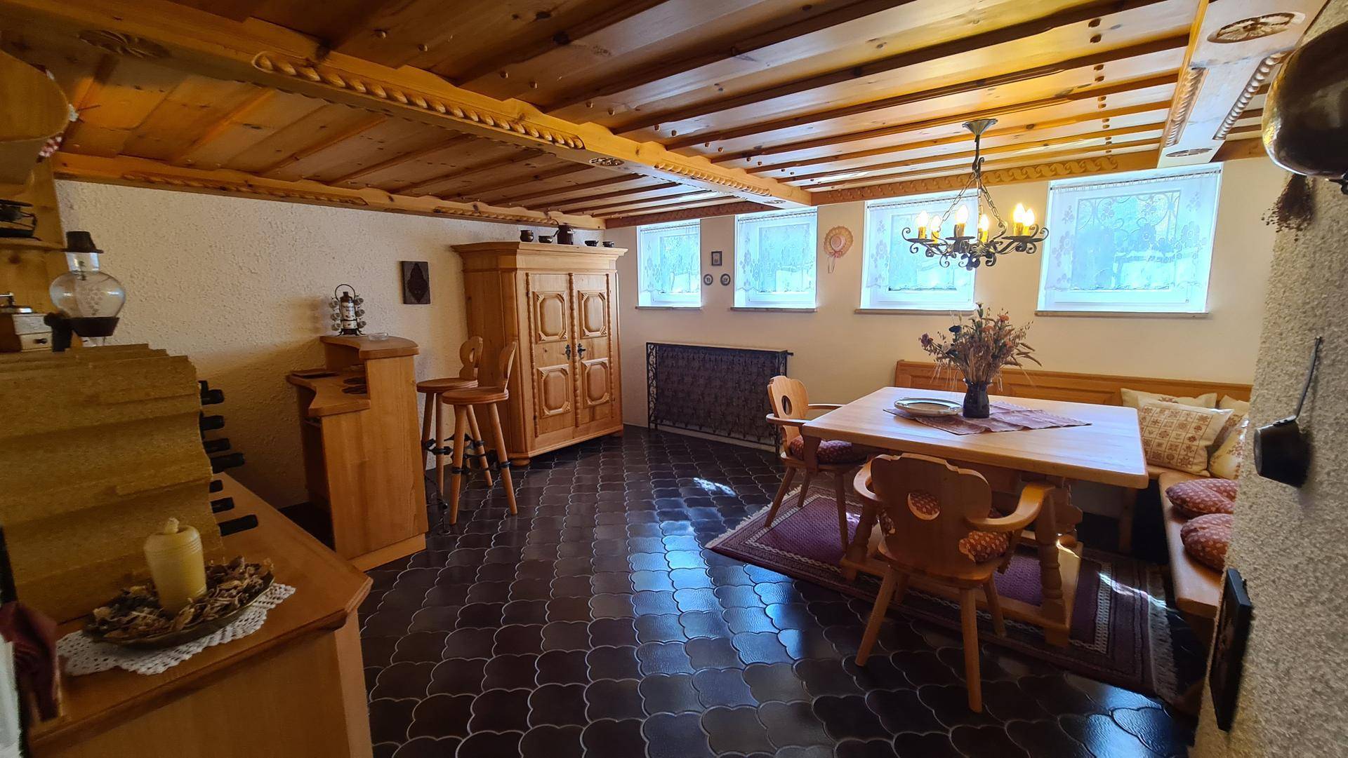 Rustikaler Essbereich mit großem Holztisch, Eckbank und traditioneller Holzdecke.